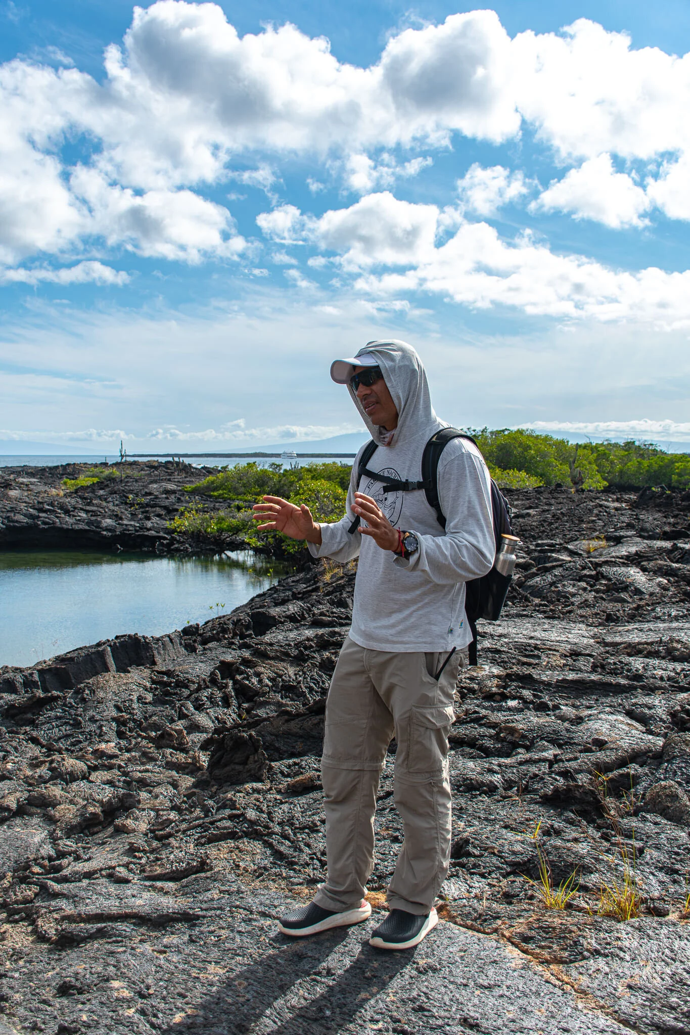 Our male guide standing on an island explaining more about what we are seeing. He is standing on lava rock and the ocean is behind him.