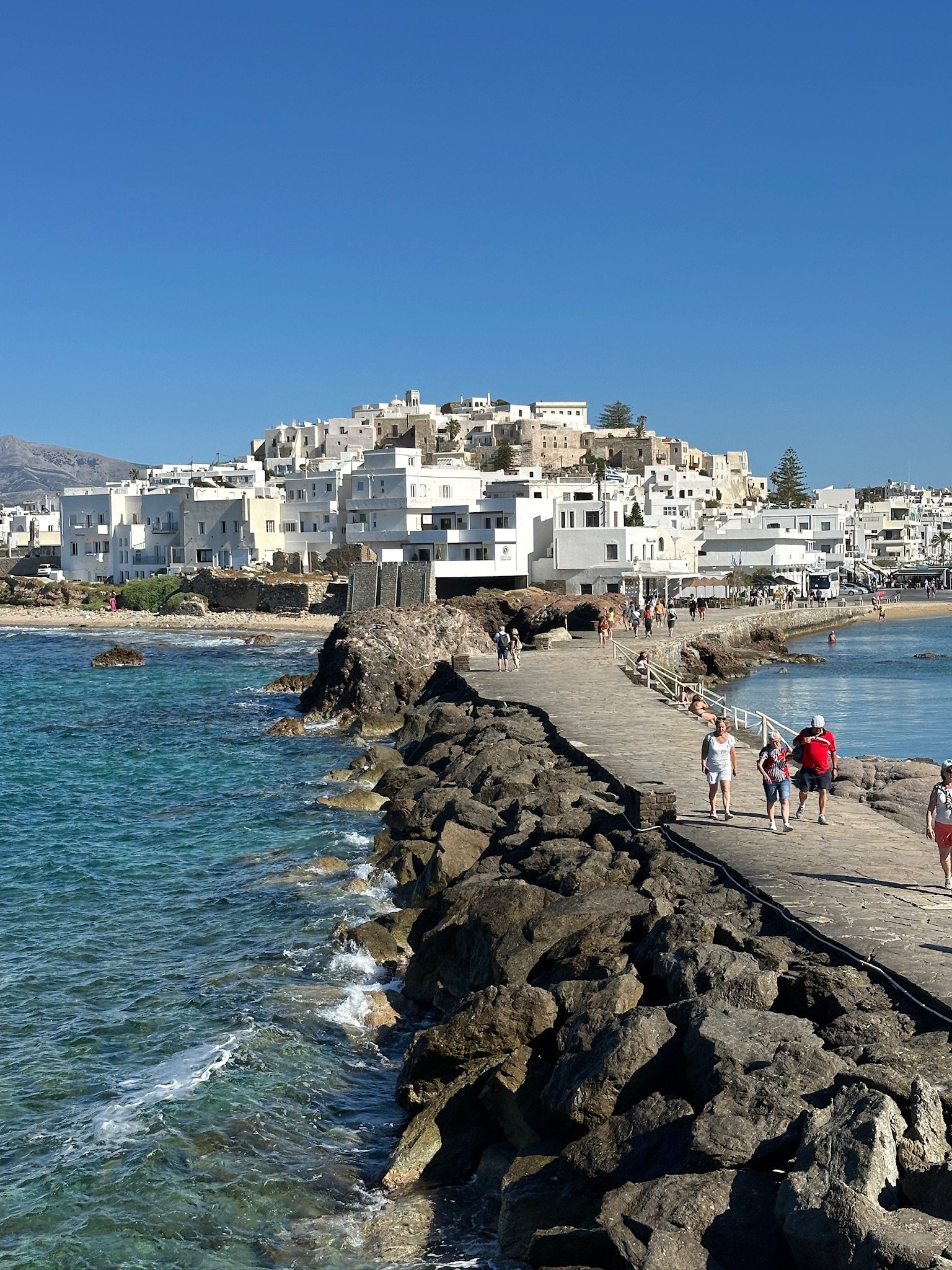 Rockbridge leading up to a whitewashed village near Naxos Greece