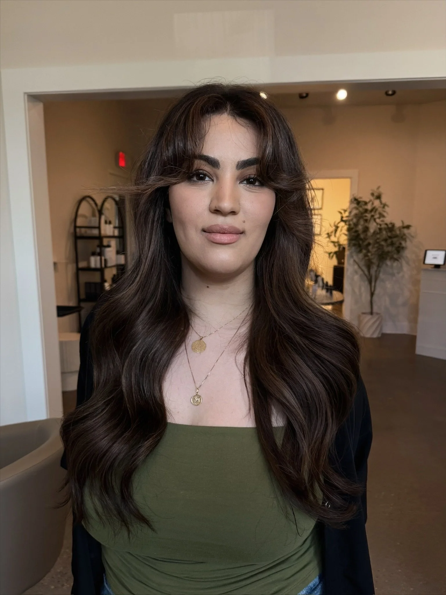 Custom color-matched and layered hand-tied extensions for fine hair clients. Brunette color with curtain bangs in Portland.