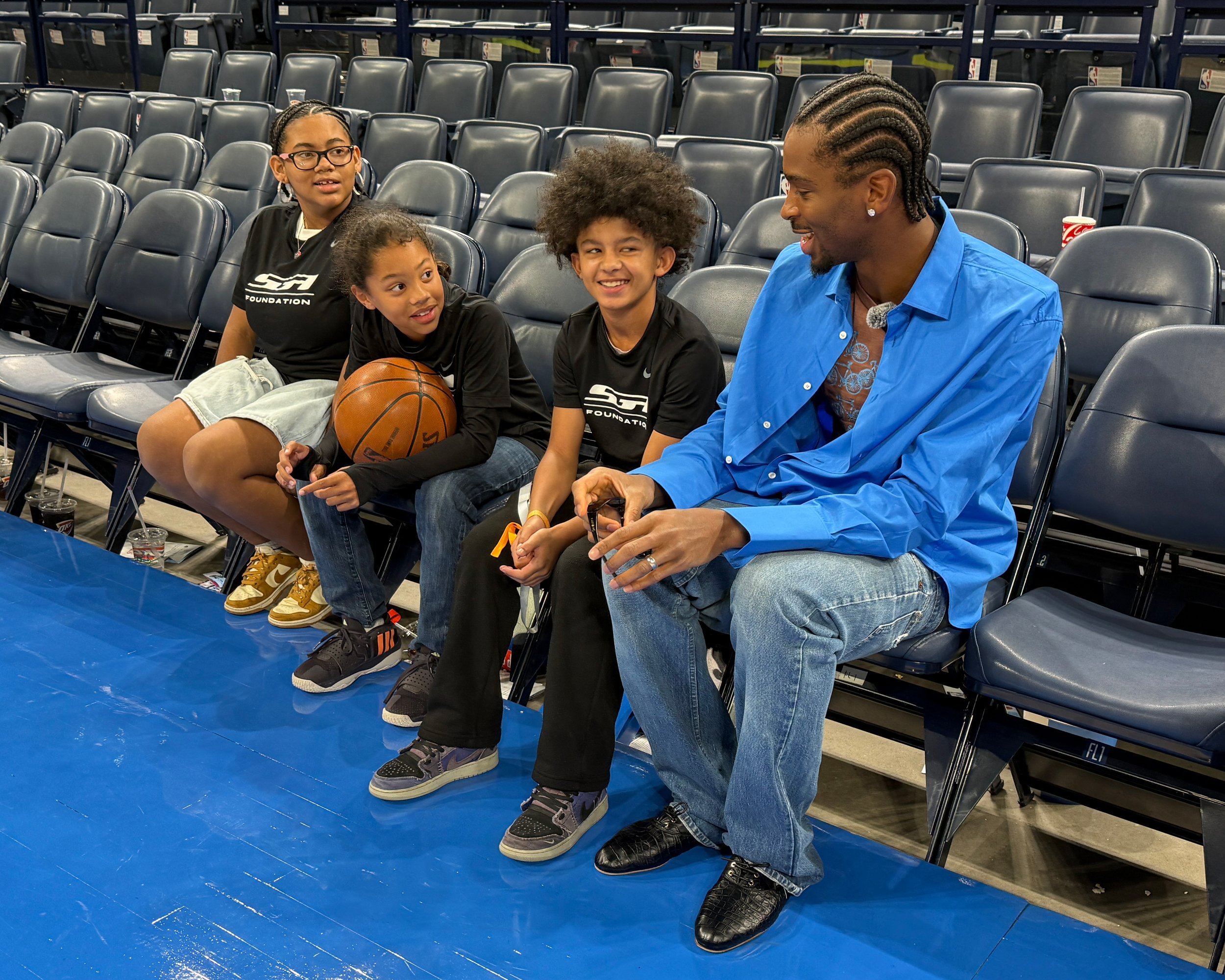 Shai Gilgeous-Alexander sits courtside with three children during an SGA Foundation and Big Brothers Big Sisters of Oklahoma partnership experience.