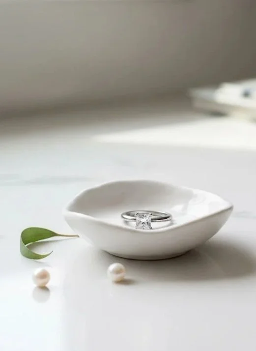 Close-up of a TIffany diamond solitaire engagement ring in a ring dish by Richer Jewelry