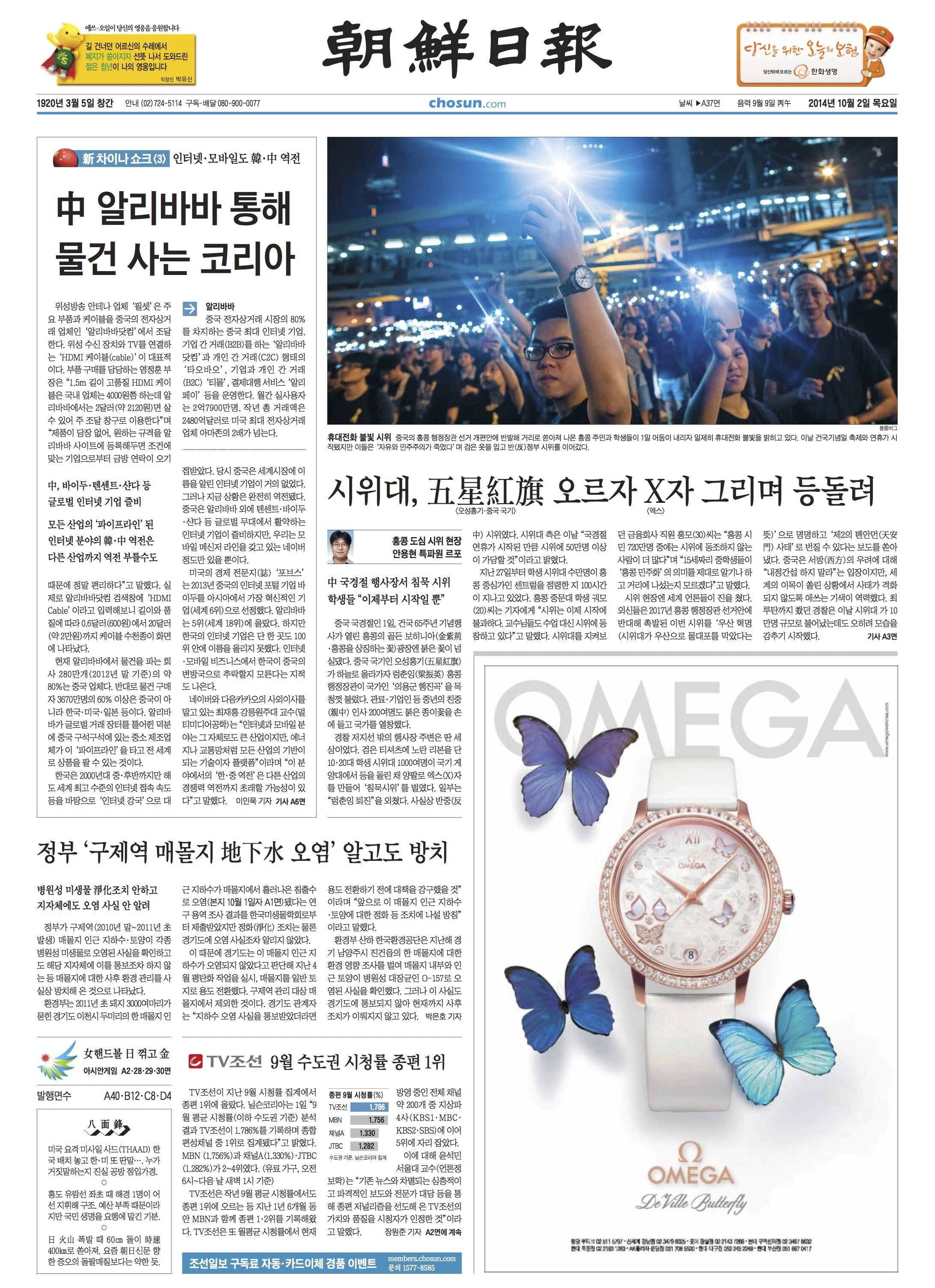 Front page of a Korean newspaper with a large photo of a crowd with bright lights at night, and a smaller advertisement for Omega Butterfly watches featuring butterflies and watches.