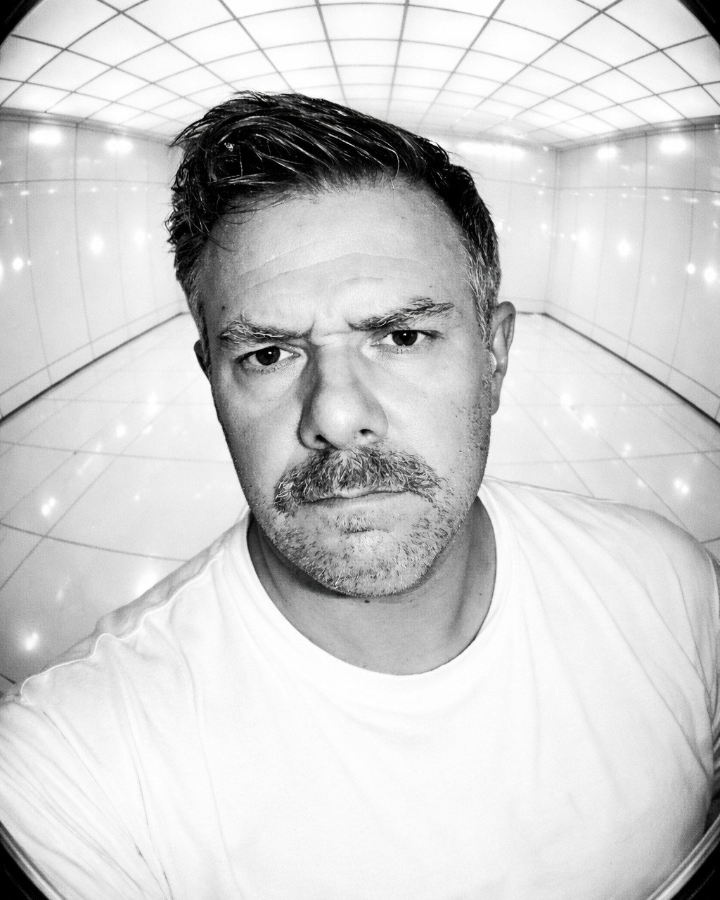 04_2026

Chat GPT:
A high-contrast, bright futuristic portrait photographed with a Hasselblad medium-format film camera using an extreme fisheye wide-angle lens and harsh on-camera flash. The space is constructed from glossy white floor panels that r