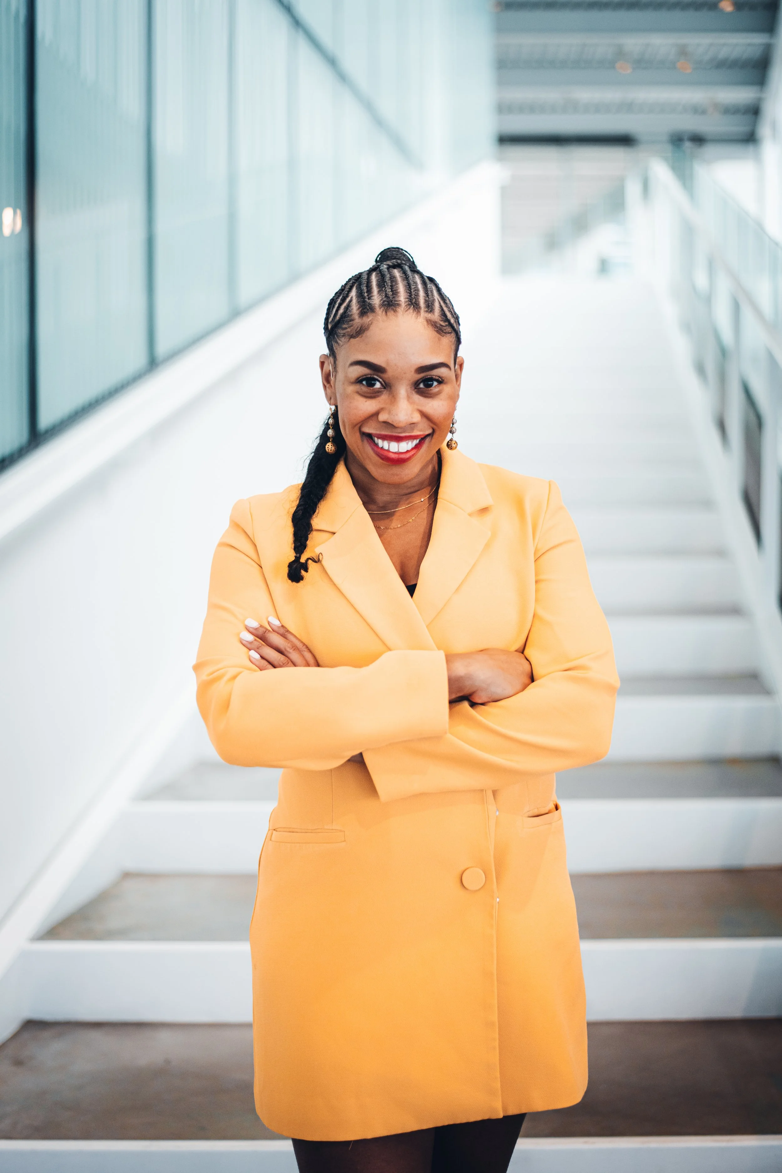 A woman with black braids, wearing a yellow blazer