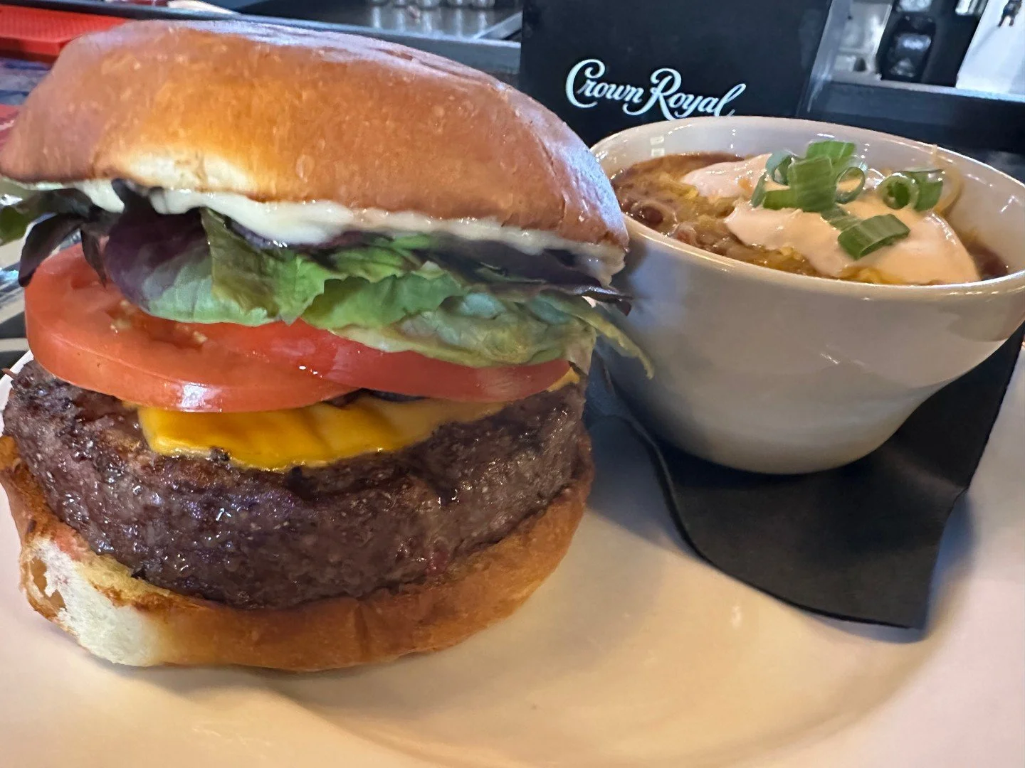 CHEESEBURGER: Half-pound beef patty with deep-fried garlic mayo, fried onions, mixed greens, tomato, and choice of cheese on a brioche bun. Pictured here with a side of CHILI!