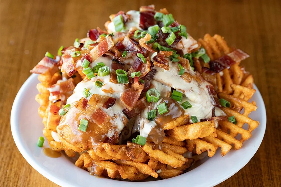 POUTINE: Waffle fries smothered in pork gravy, gouda jalapeno cheese sauce, and bacon, garnished with green onions