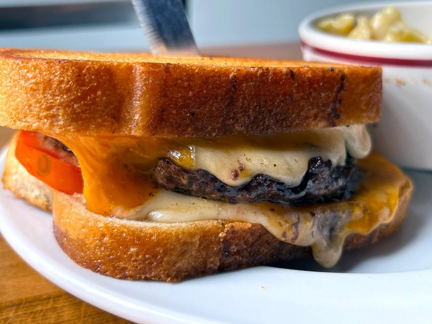 FRISCO MELT: choice of a half-pound beef or veggie patty with cheddar, Swiss, tomato, and Frisco sauce on grilled sourdough! Pictured here with a side of MAC AND CHEESE.