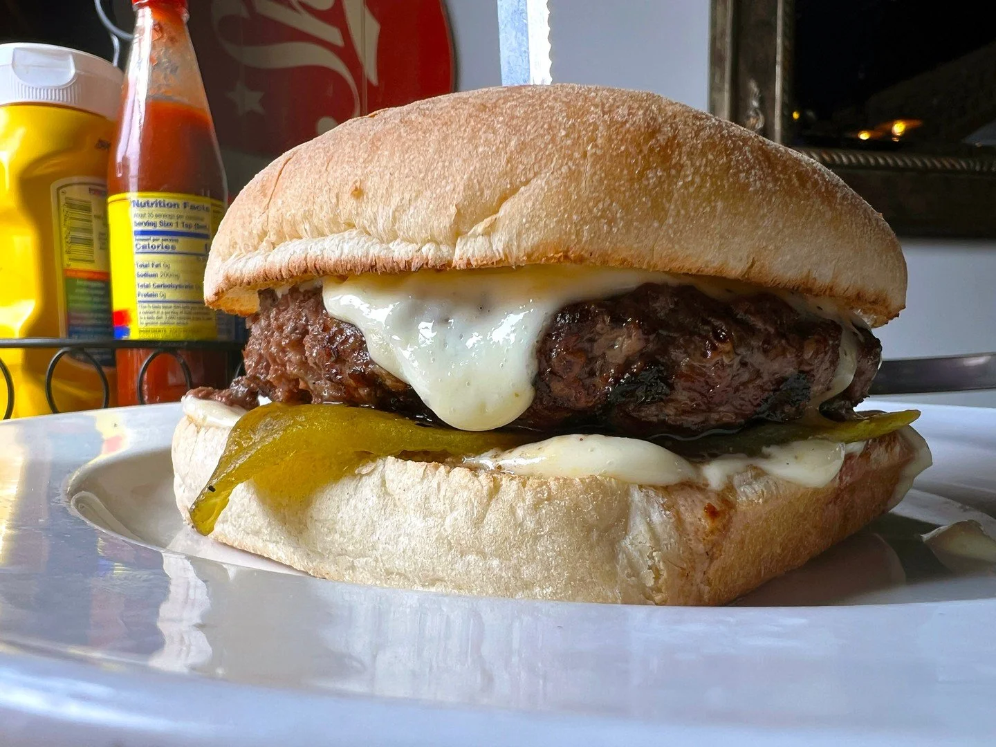 A Green Chile Burger featuring a choice of a half-pound beef patty or a Hungry Planet veggie patty, topped with roasted green chiles, horseradish sauce, and a gouda jalape&ntilde;o cheese sauce on a ciabatta bun. Served with a choice of side.