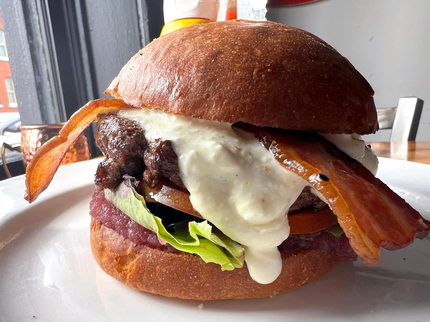 PRINCESS BUTTERCUP: choice of half-pound beef or Hungry Planet veggie patty, served with mixed greens, tomato, whipped garlic feta, bacon, and onion jam on a brioche bun. Comes with a choice of side.