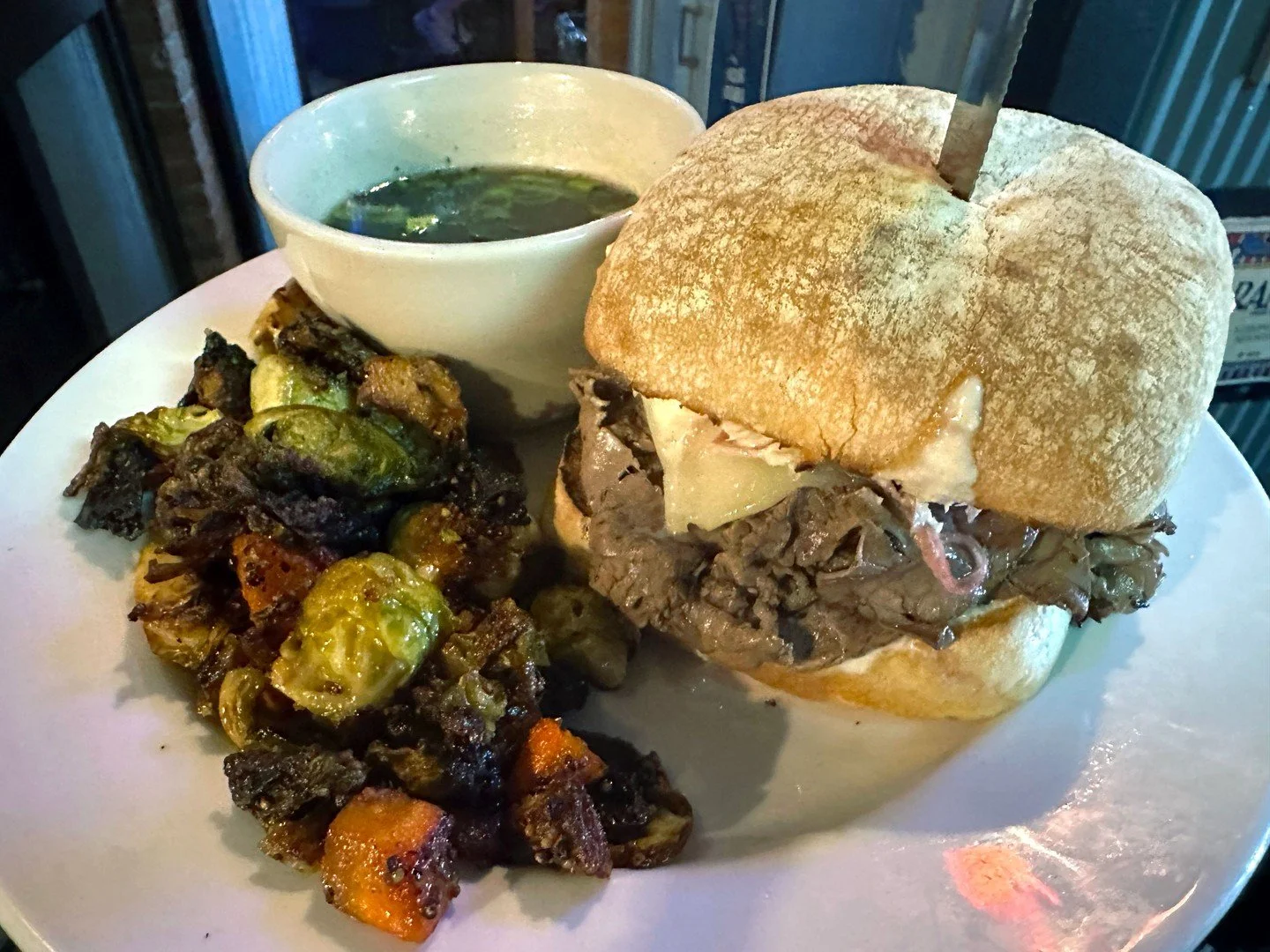 French Dip: Tender, house-cut roast beef with Swiss cheese, marinated red onions, and horseradish sauce on ciabatta, served with au jus. Accompanied here by roasted Brussels sprouts.

#EatCrowSTL #Soulard #STLFood #STLEats #StLouisFood #StLouisEats #