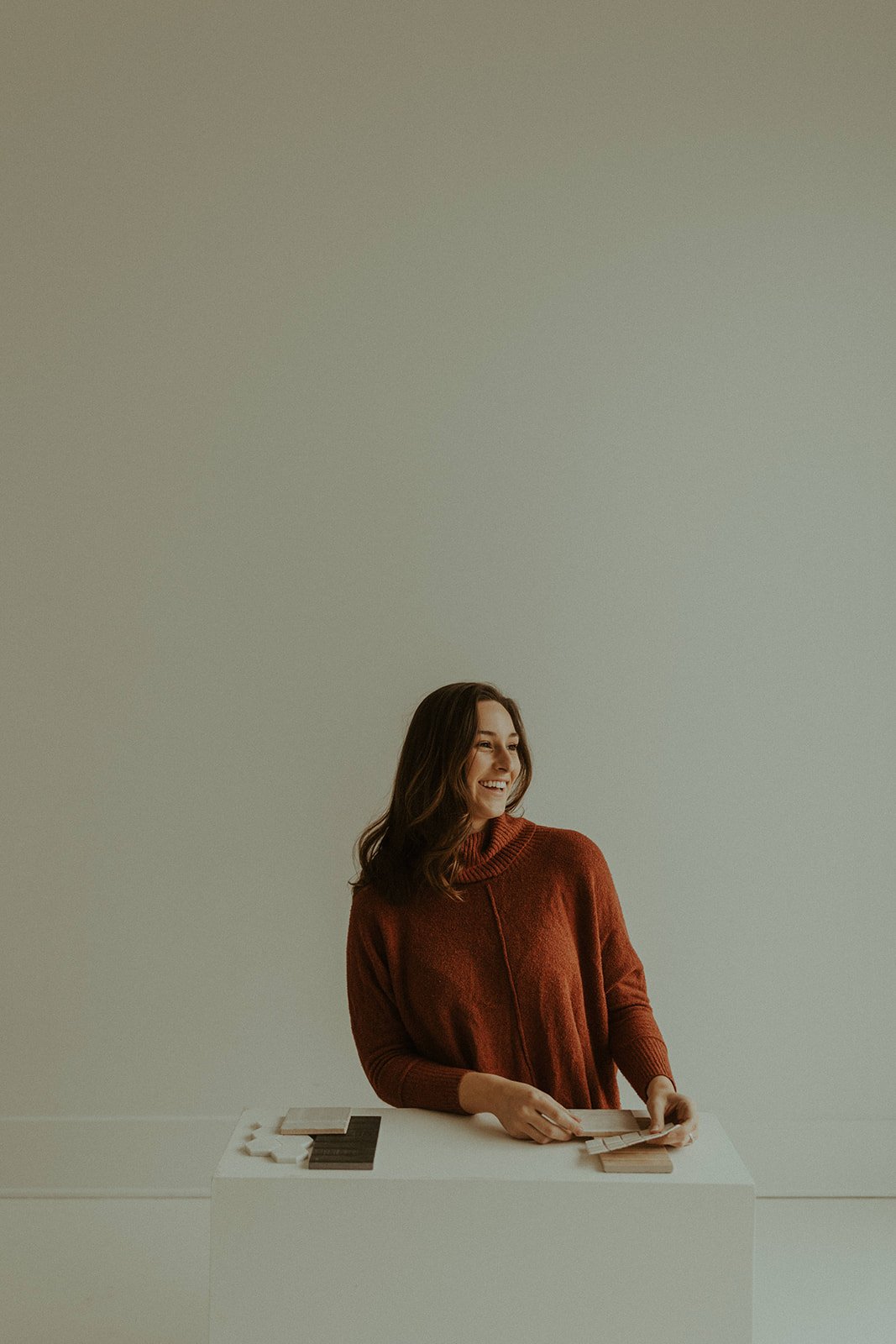smiling woman in red shirt works with tile and material samples