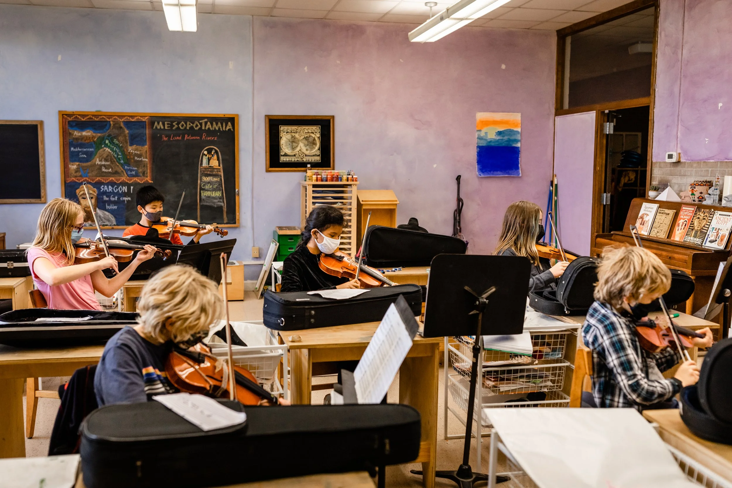 Middle School students sit in a classroom playing violins in their strings speciality class at the Prairie Moon Waldorf School in Lawrence Kansas. Music curriculum is a part of middle school. .