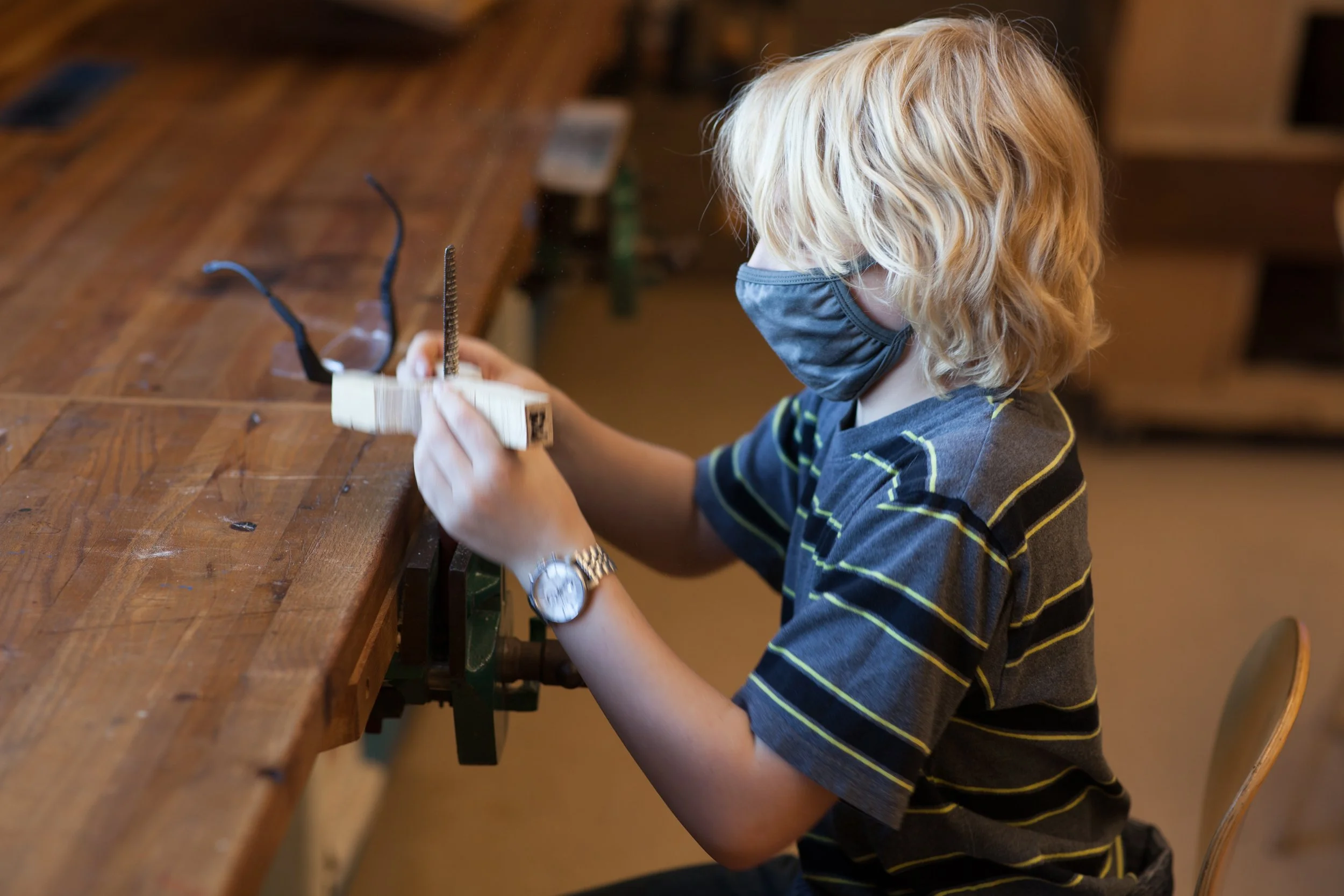A middle school student is holding a woodworking vice as they clamp it in place for a hands on project in a screen-free environment at the Prairie Moon Waldorf School in Lawrence Kansas.
