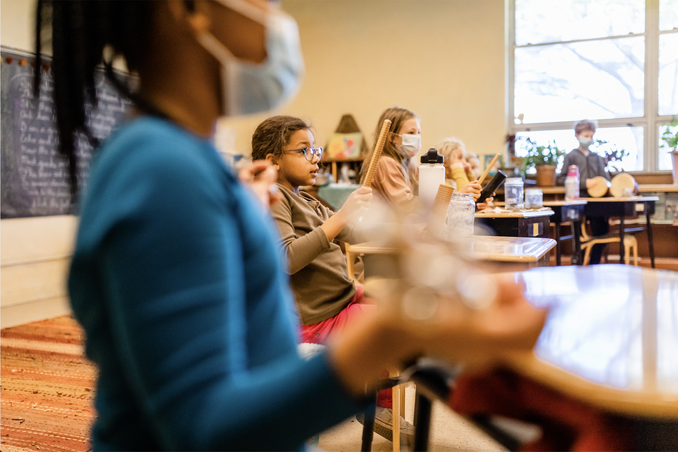 Three students playing music in 5th grade at the Prairie Moon Waldorf School in a classroom. Speciality classes include music, strings, world language and movement.