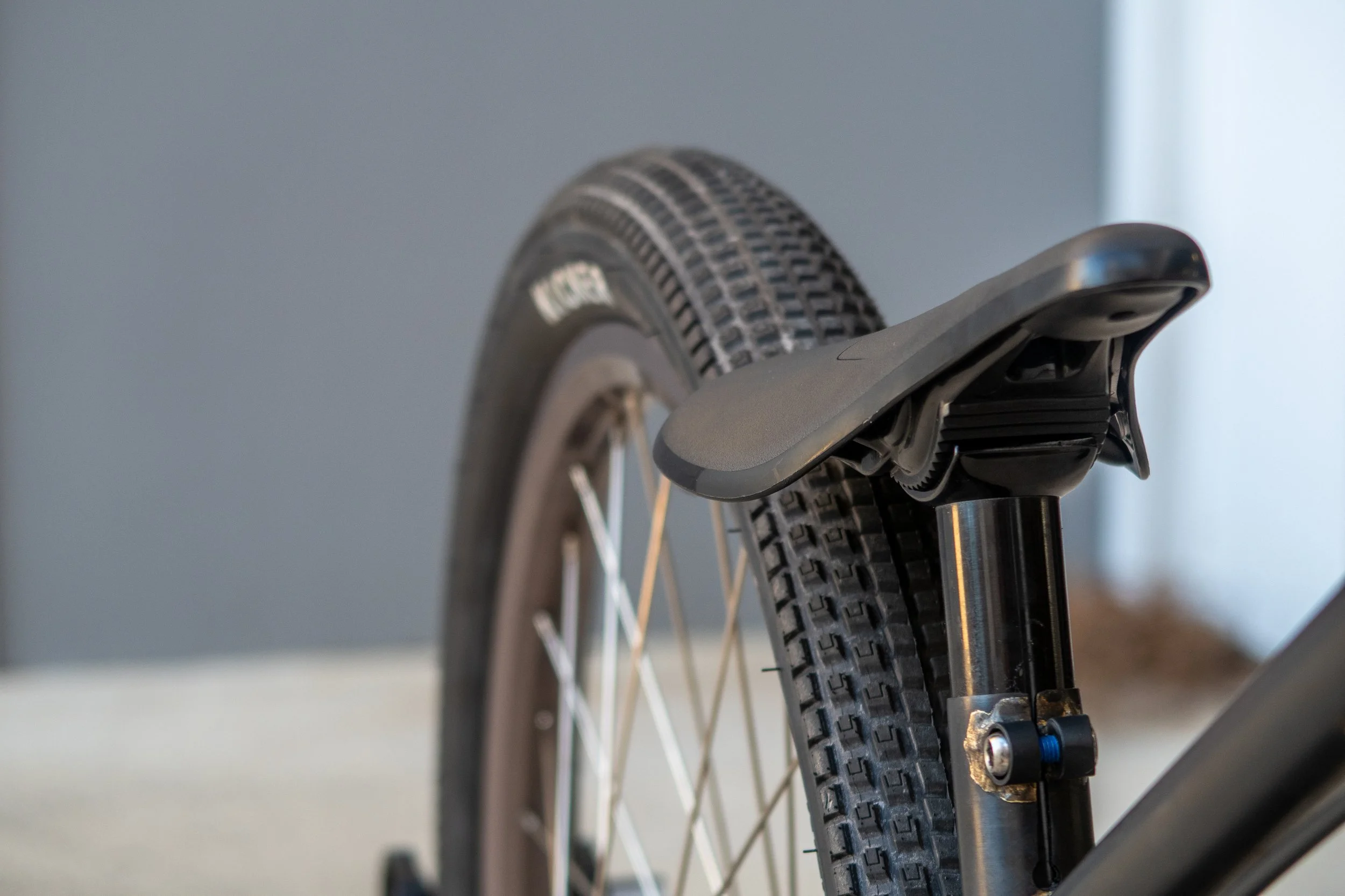 Close-up view of a bicycle's rear wheel and saddle, showing the tire, spokes, and part of the seat post.