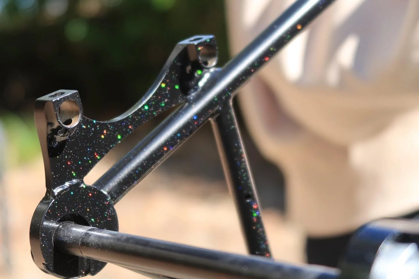 Close-up of a bicycle frame with a black, sparkly paint finish that includes small multicolored glitter particles