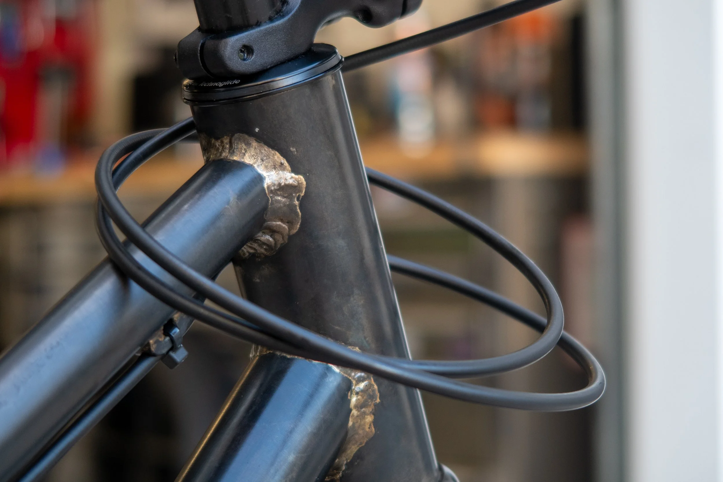 Close-up of a bicycle frame with visible welds and a cable loop.
