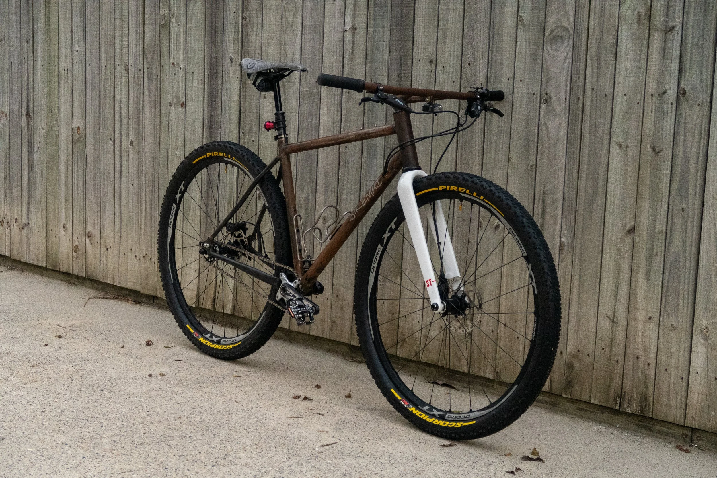 A mountain bike leaning against a wooden fence on a concrete surface.