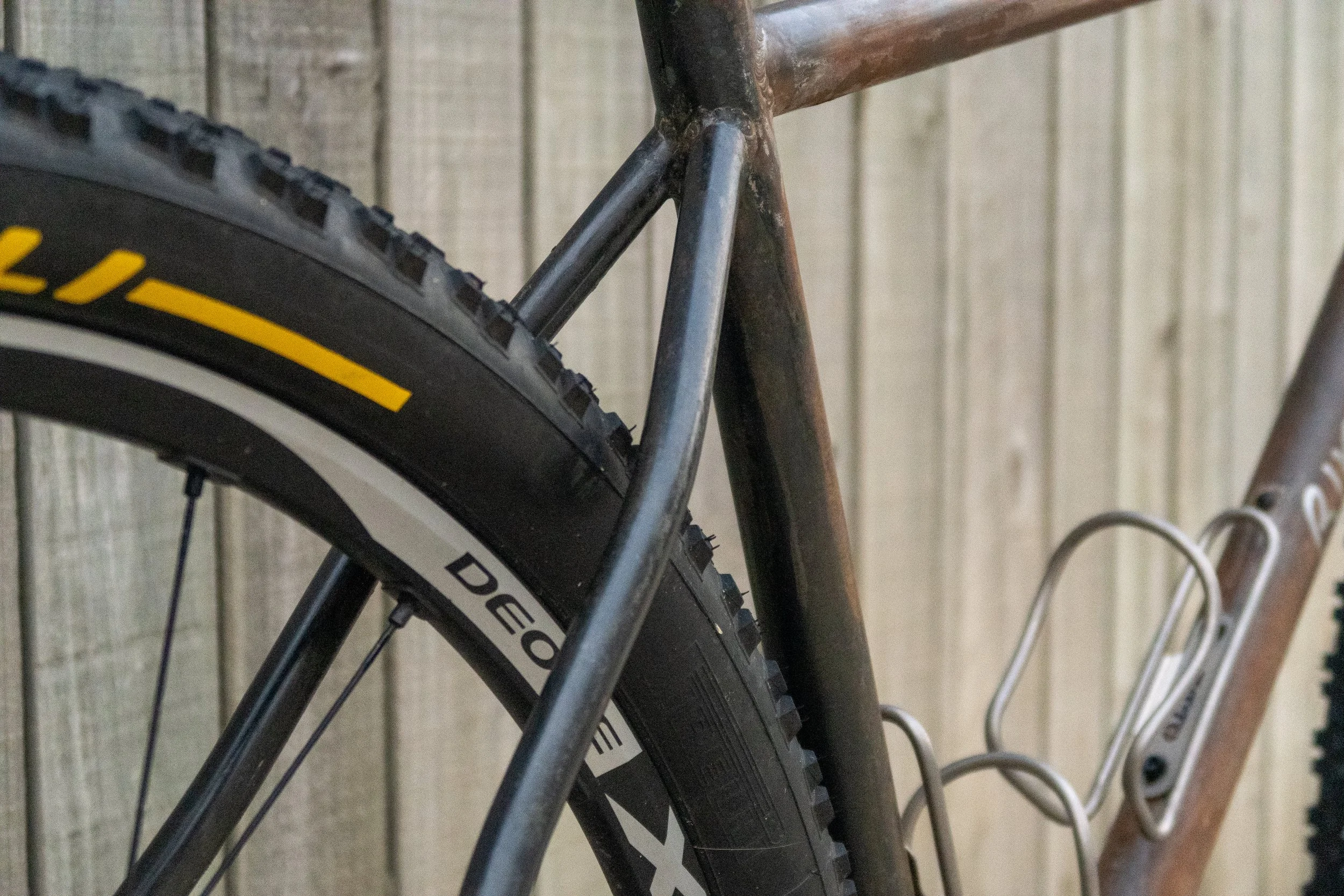 Close-up of a mountain bike tire and frame against a wooden background.