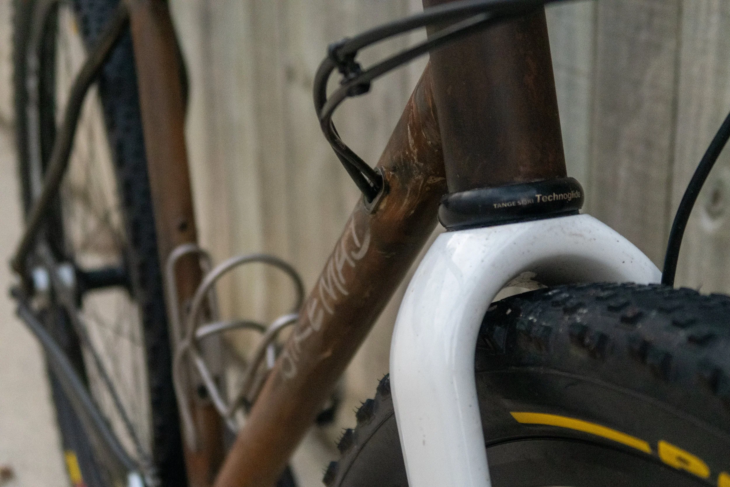 Close-up of a mountain bike's front suspension fork and frame, showing the tire, and cables.