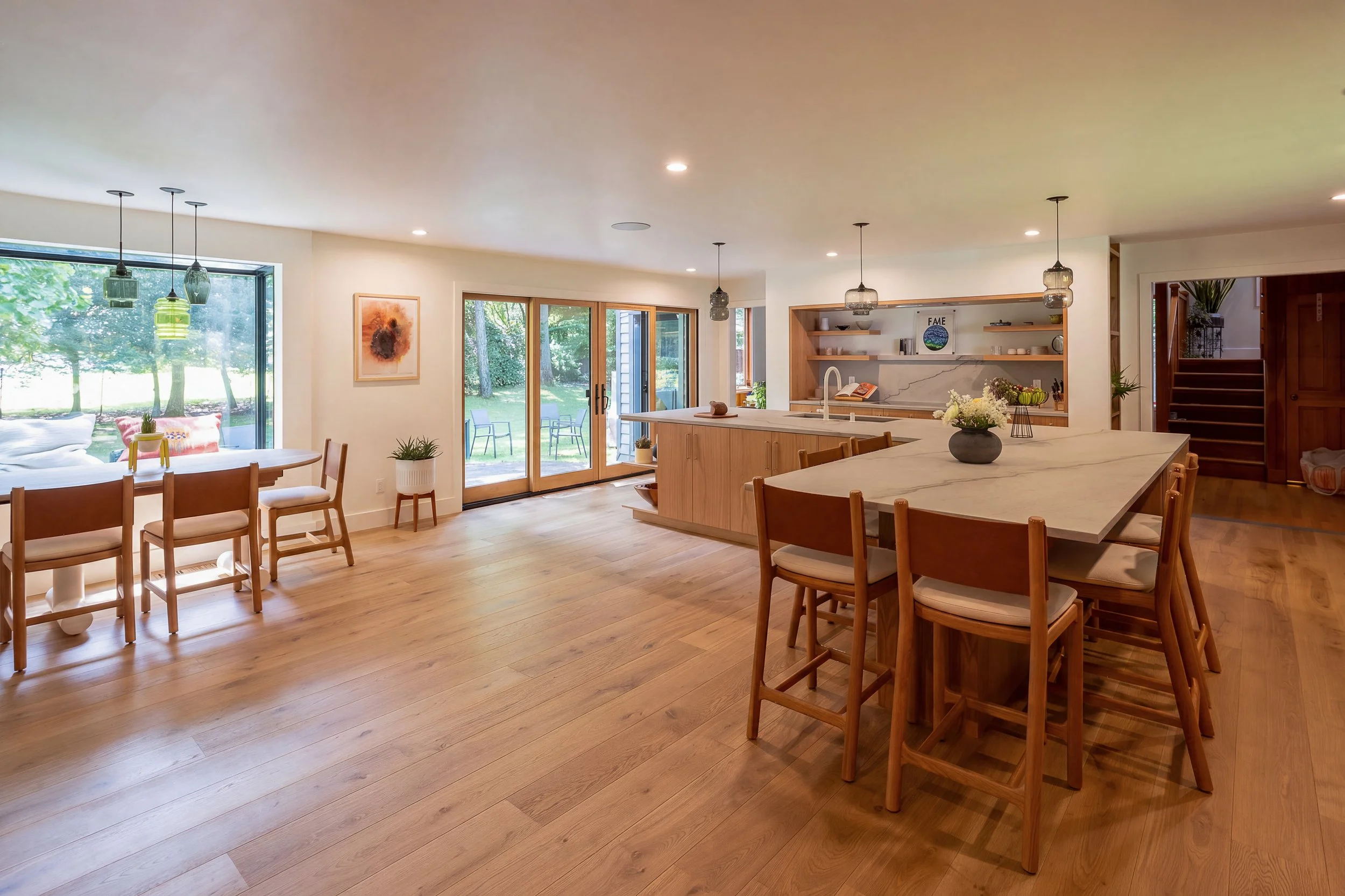 a wide angle of a kitchen with a large L-shape island, wood cabinets and white countertops and backsplash