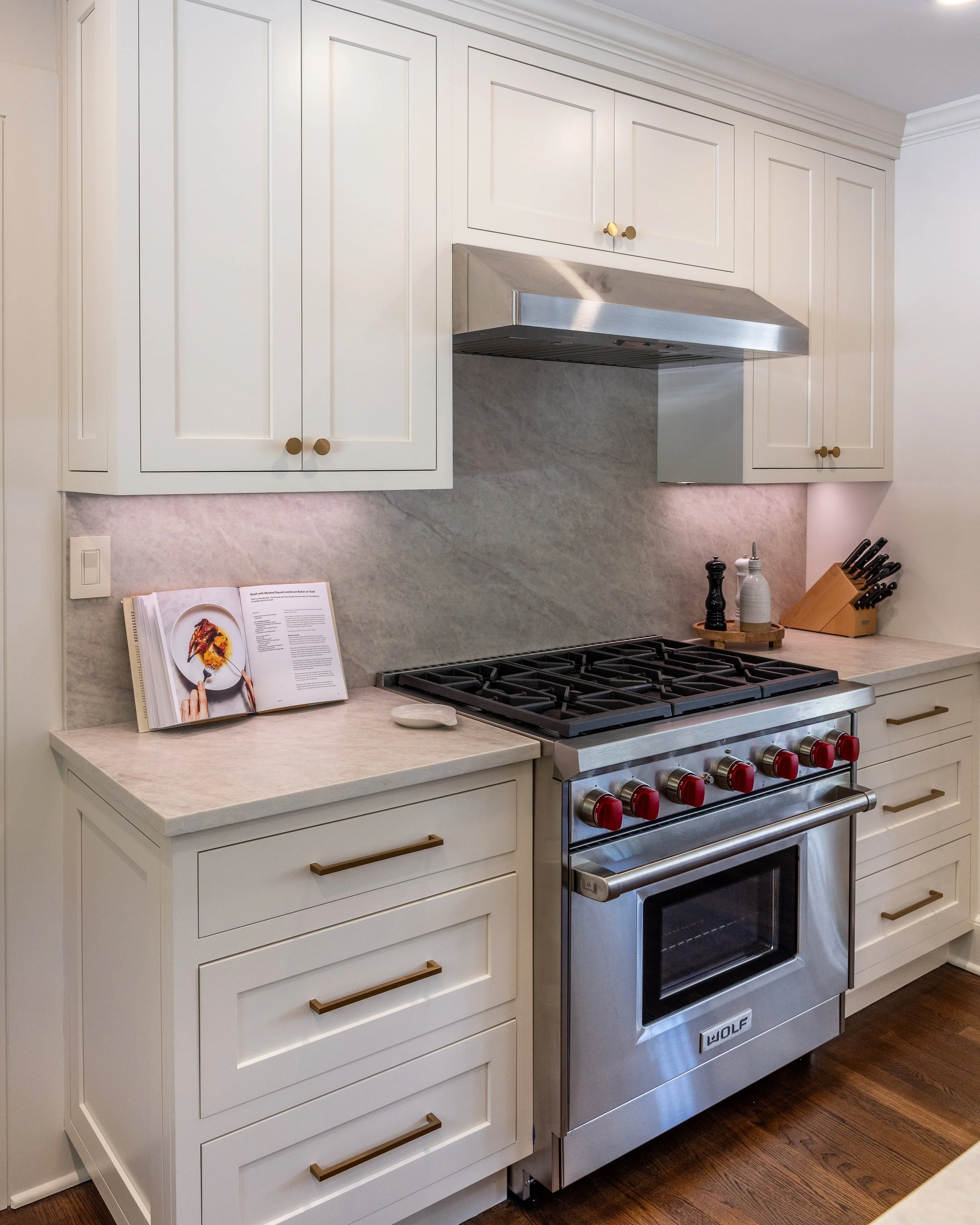 a stainless range surrounded by white cabinets