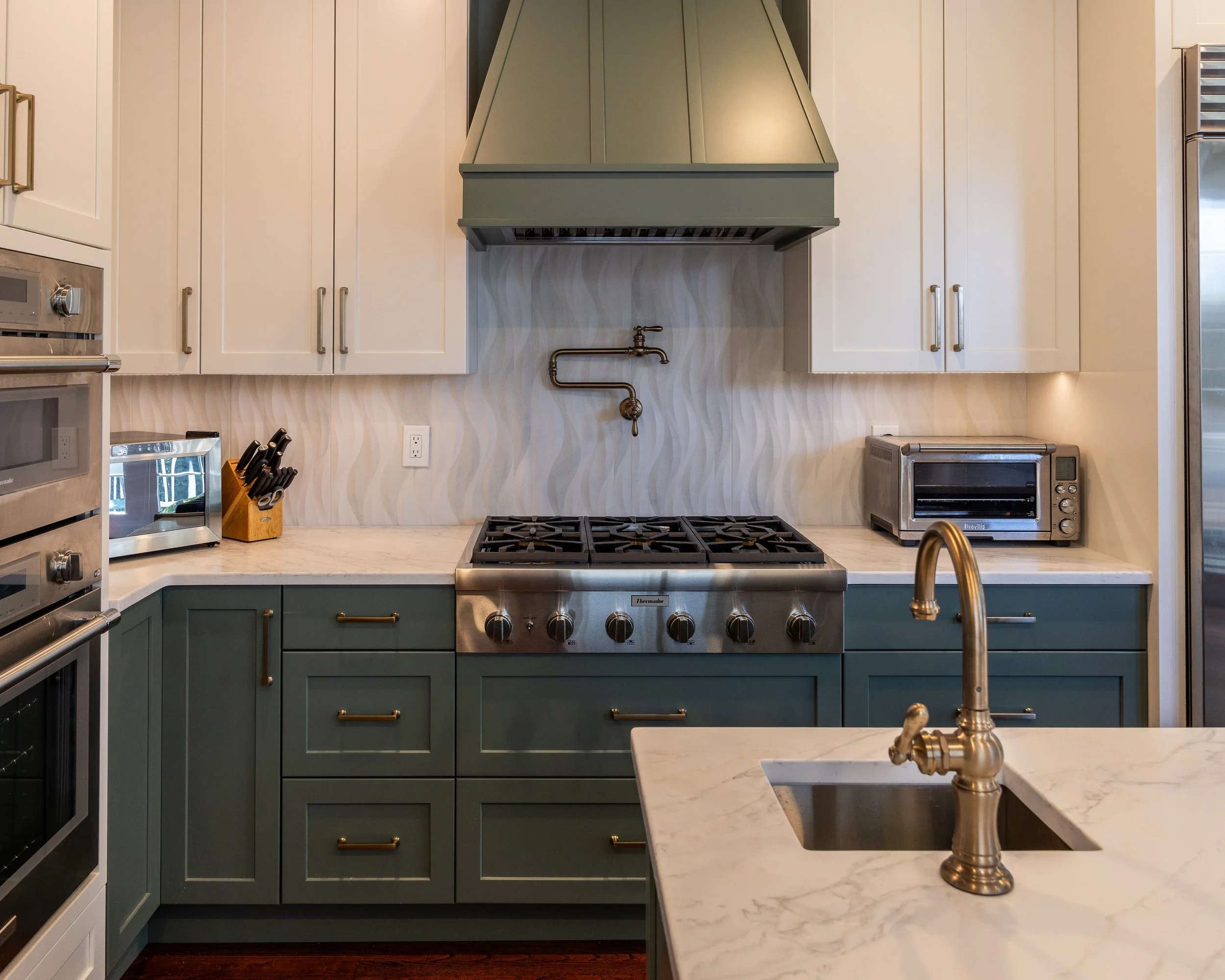 white upper cabinets and green bases with a green hood over the stove