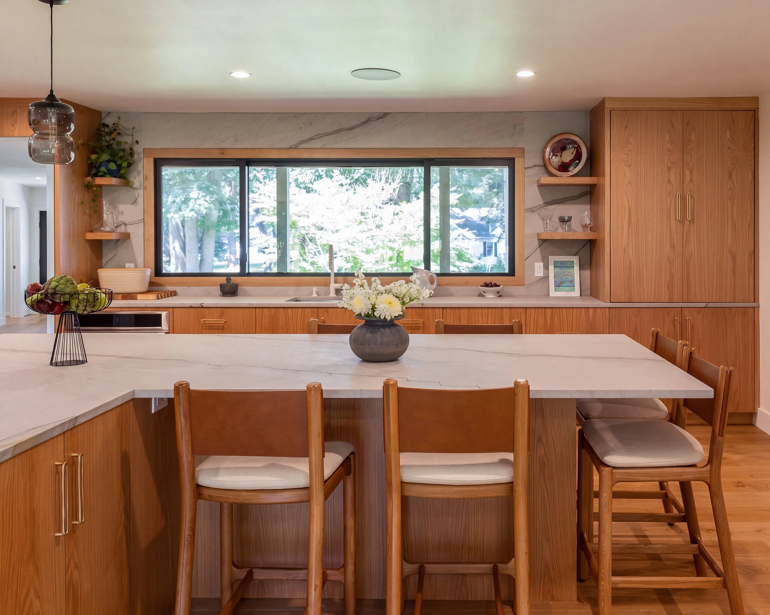 a kitchen with a large L-shape island, wood cabinets and white countertops and backsplash