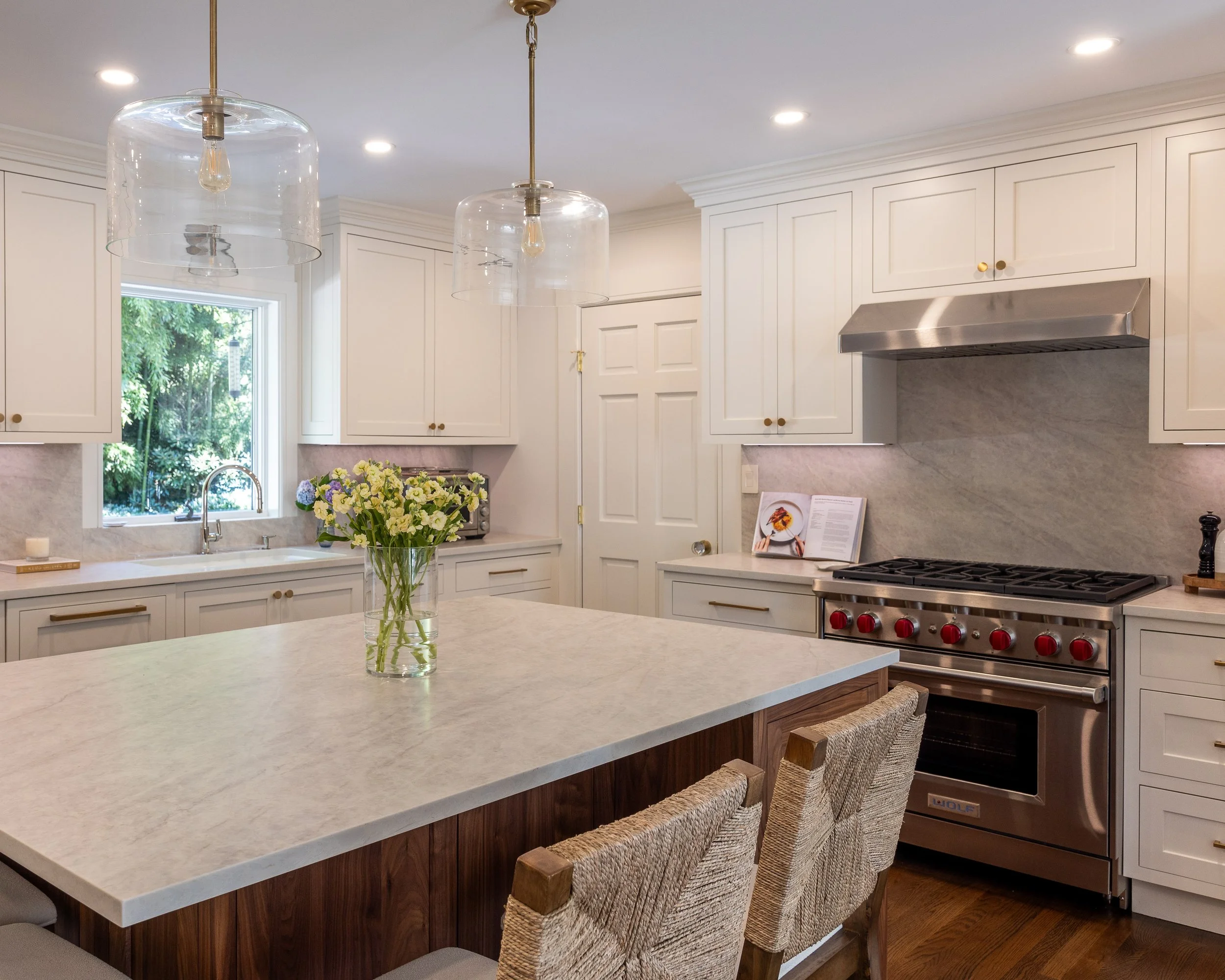 a kitchen with white cabinets, stainless appliances, and gray countertops and backsplash