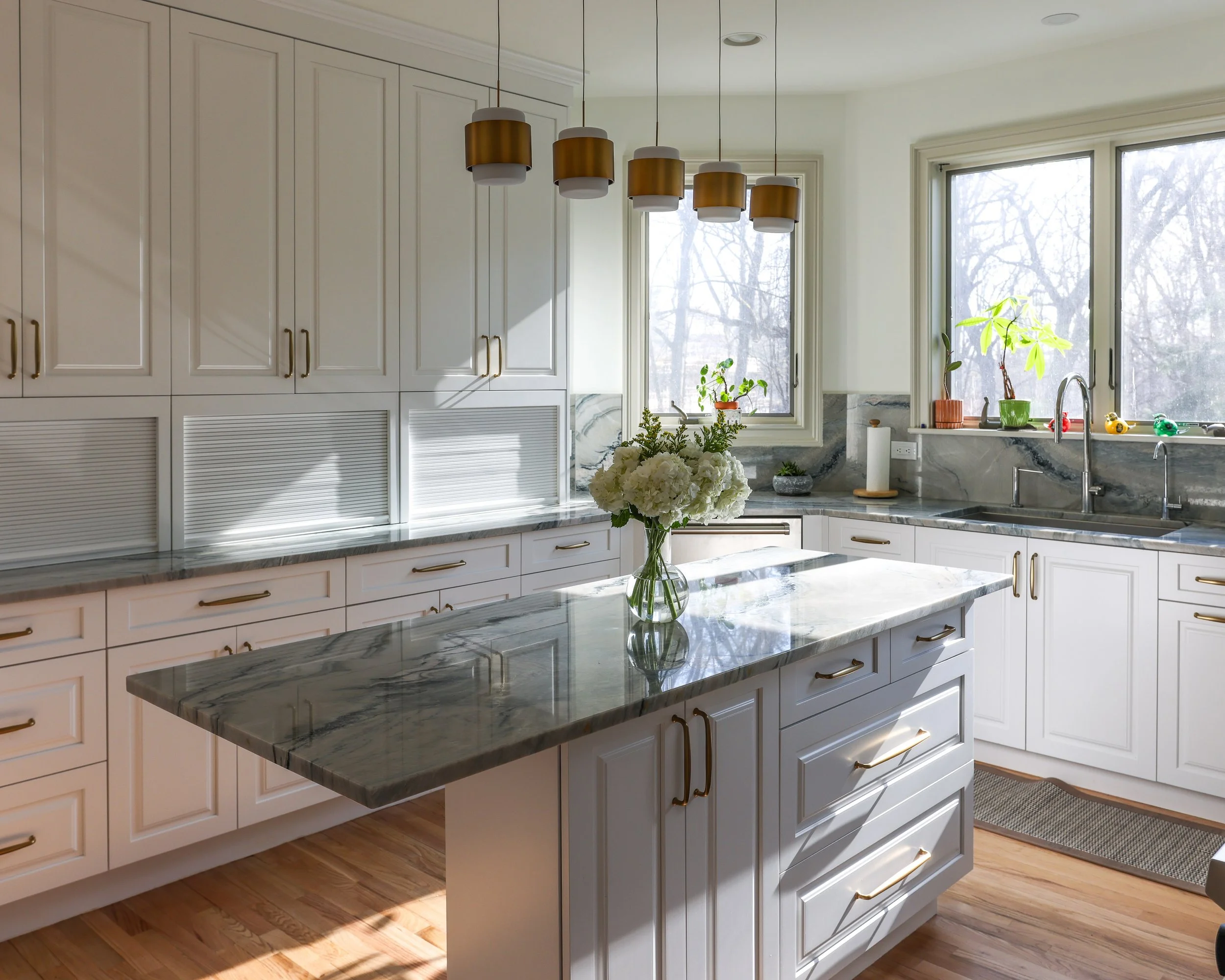 a kitchen with white cabinets and grey stone countertops