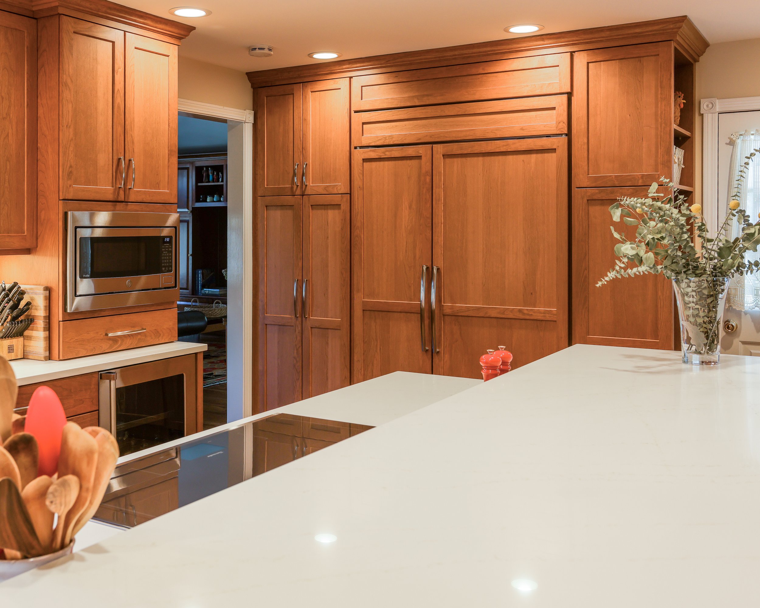 a large two-tiered island with cabinets visible behind it and a large paneled fridge