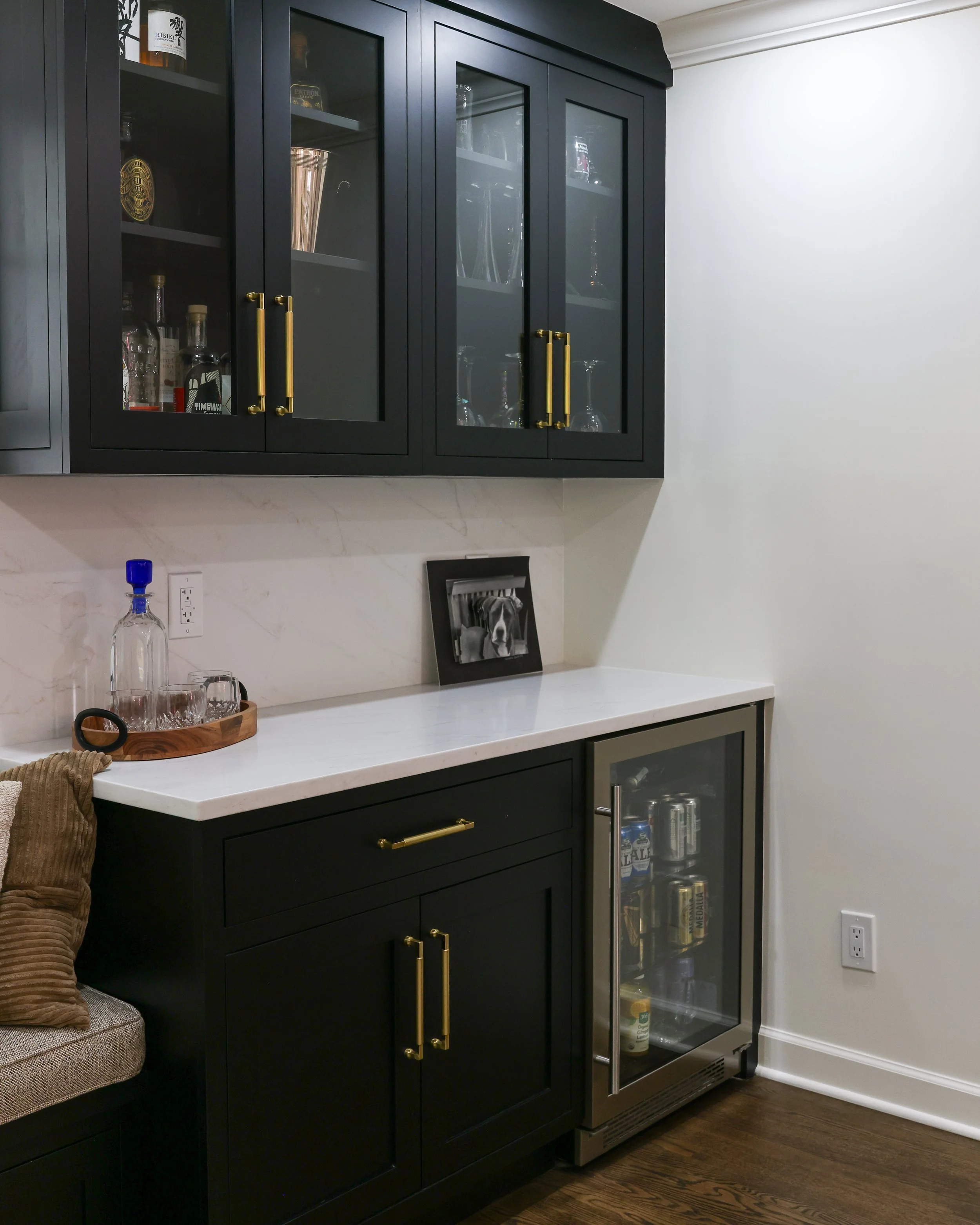 a bar with a built in fridge and black cabinets