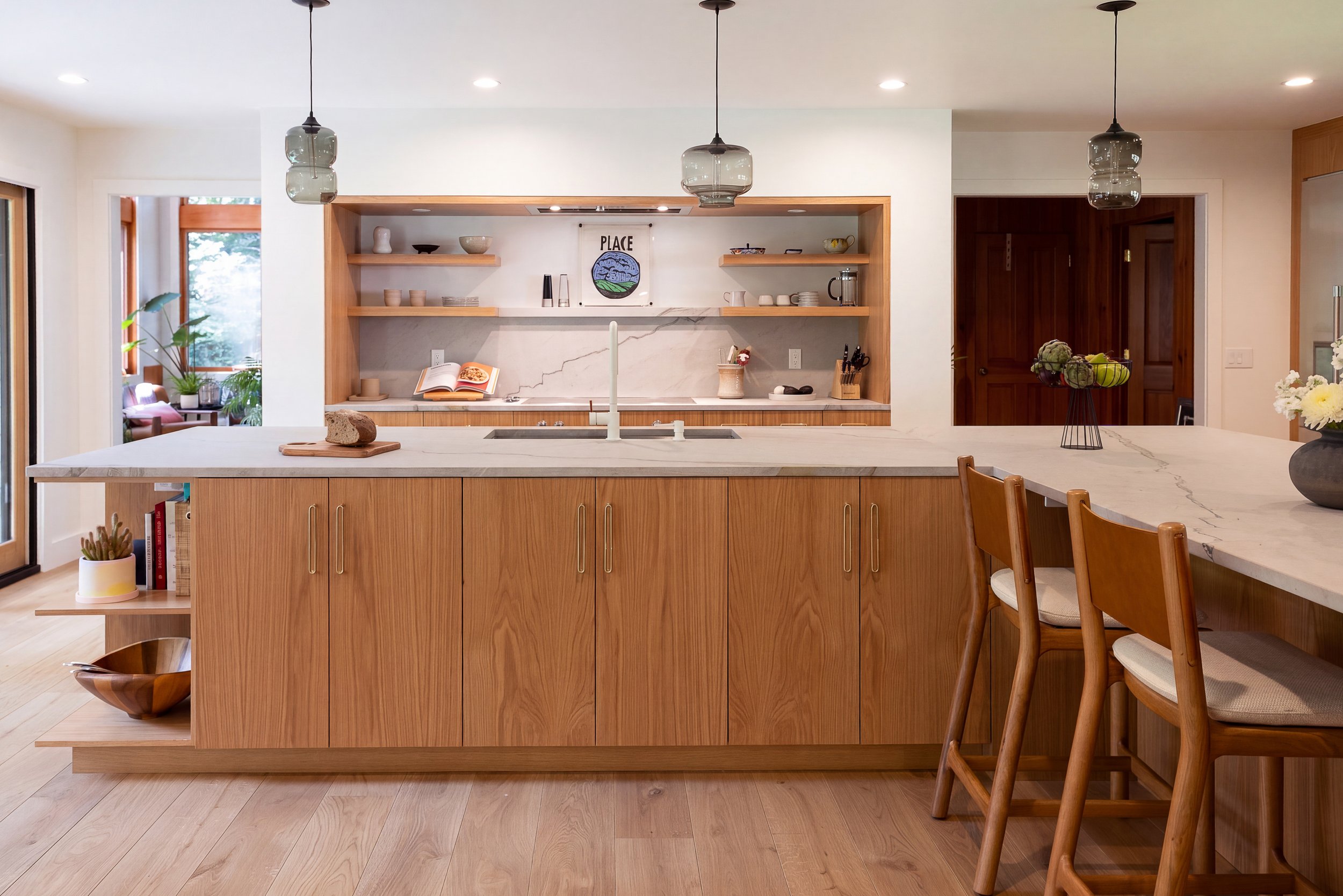 a kitchen with a large L-shape island, wood cabinets and white countertops and backsplash
