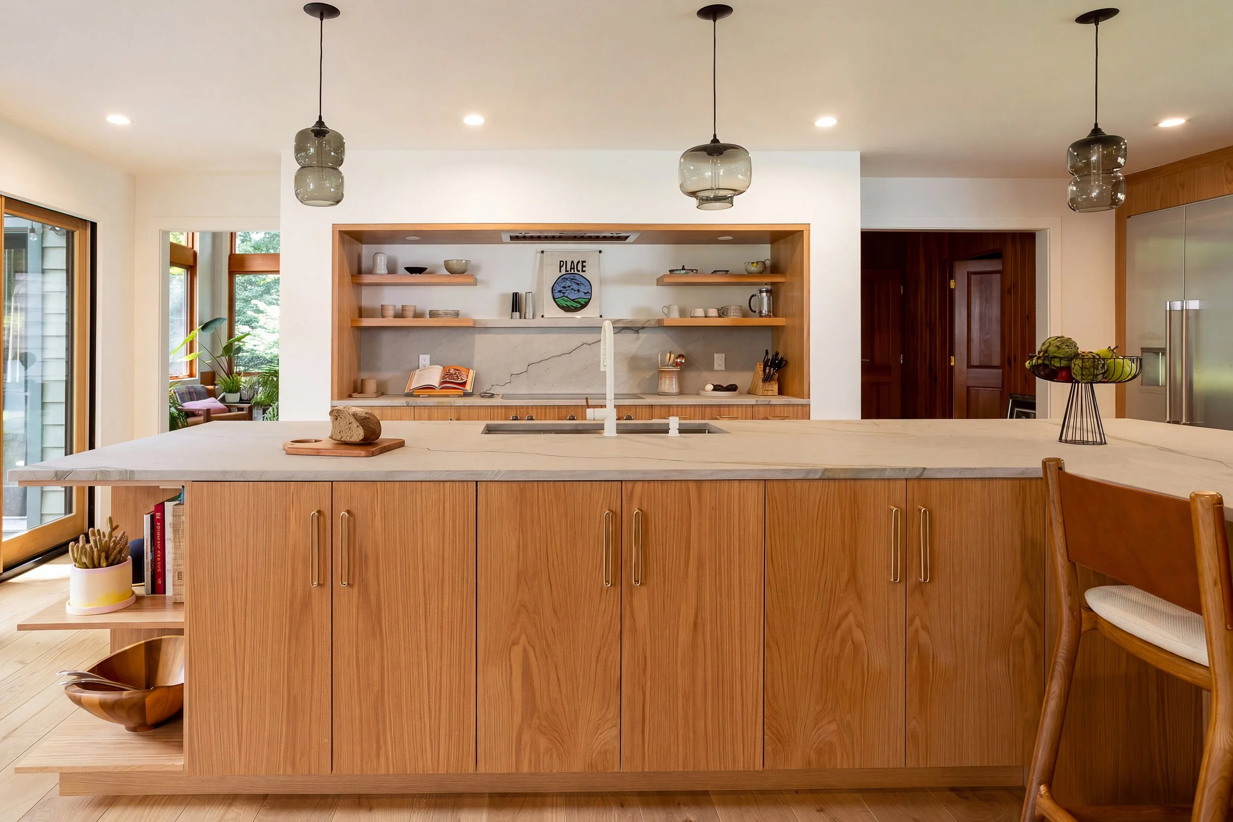 a kitchen with a large L-shape island, wood cabinets and white countertops and backsplash