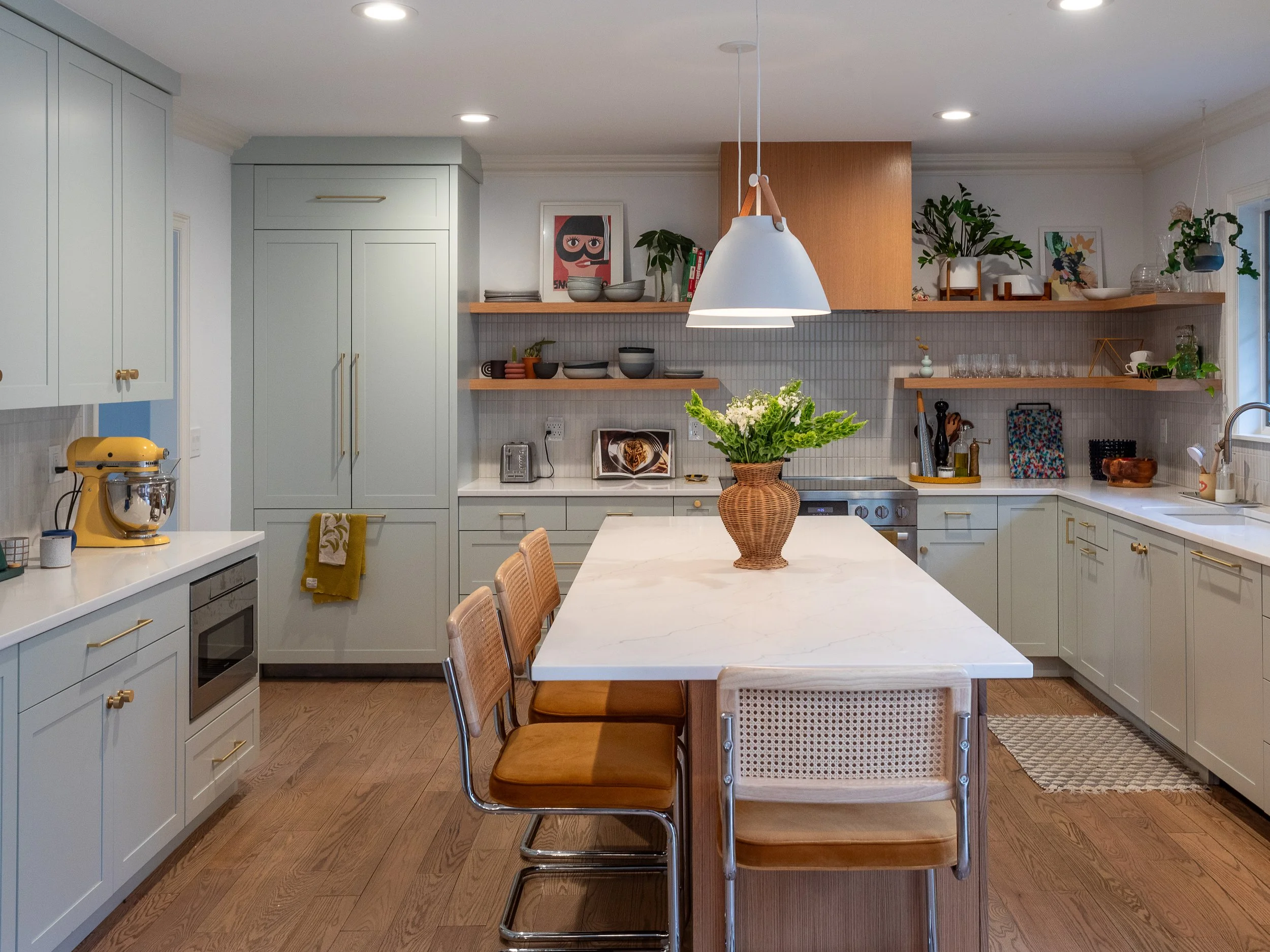 A kitchen with mostly light blue/green cabinets and a wooden hood range