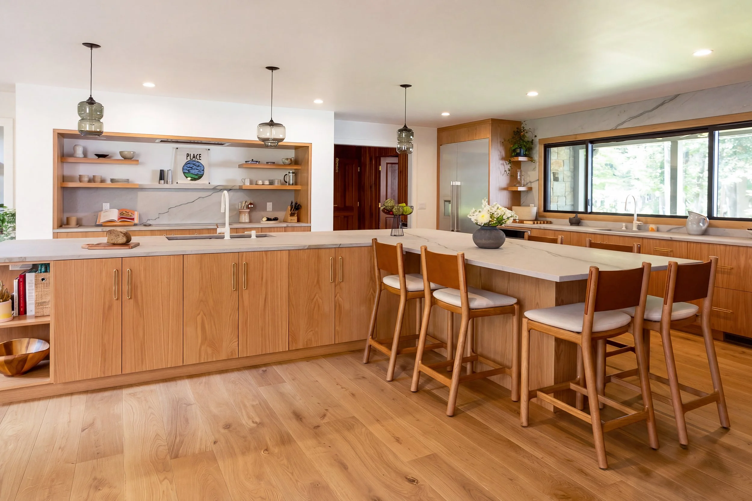 a kitchen with a large L-shape island, wood cabinets and white countertops and backsplash