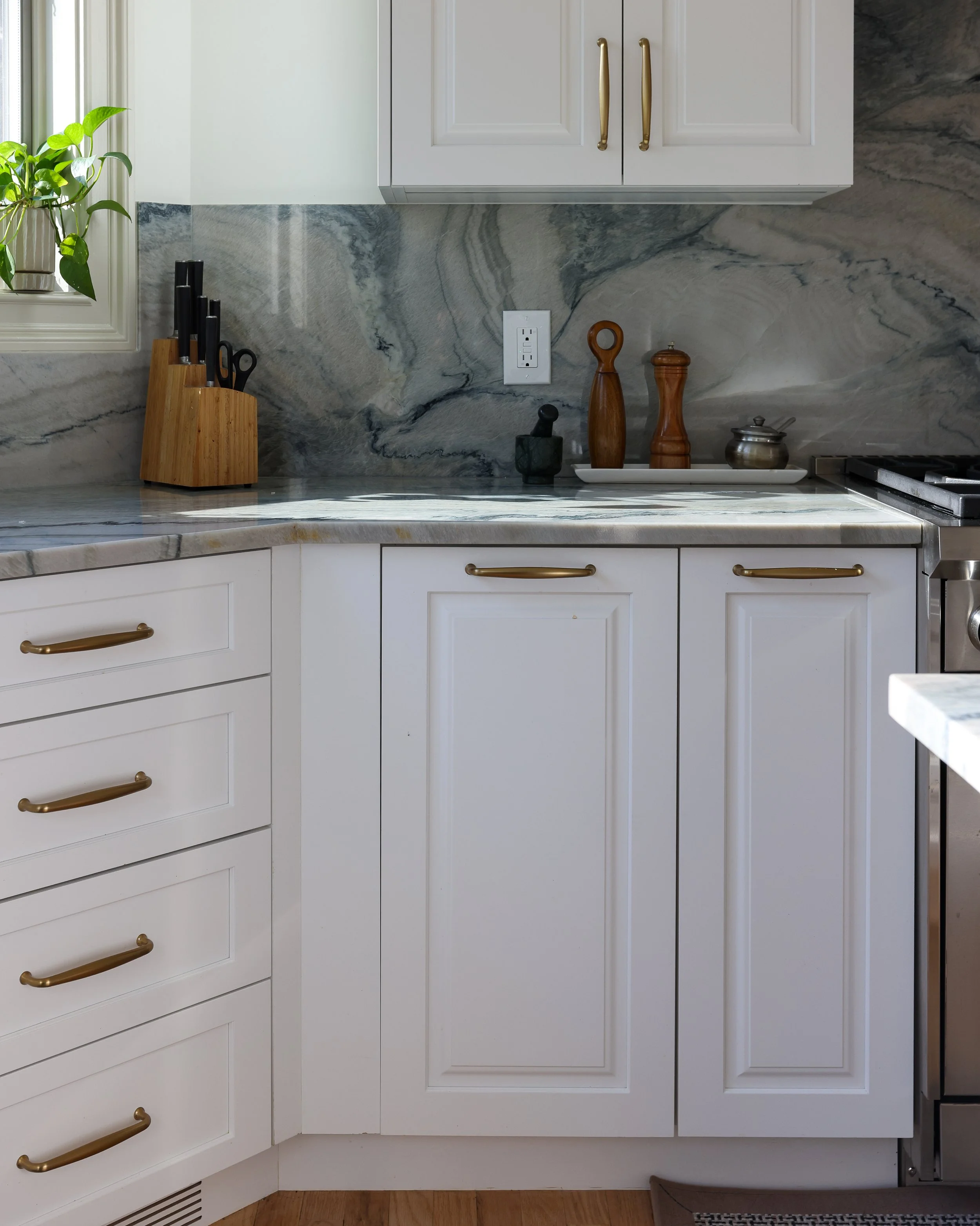 corner of a kitchen with white cabinets and grey stone countertops