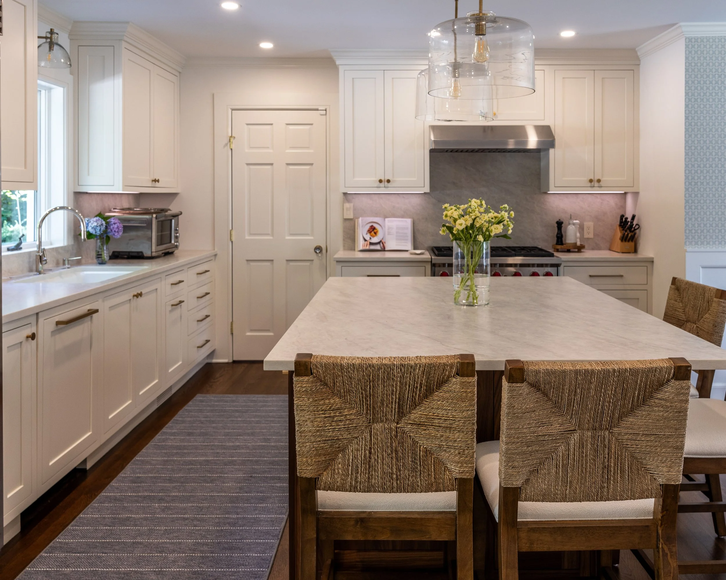 a kitchen with white cabinets and a large island with counter seats