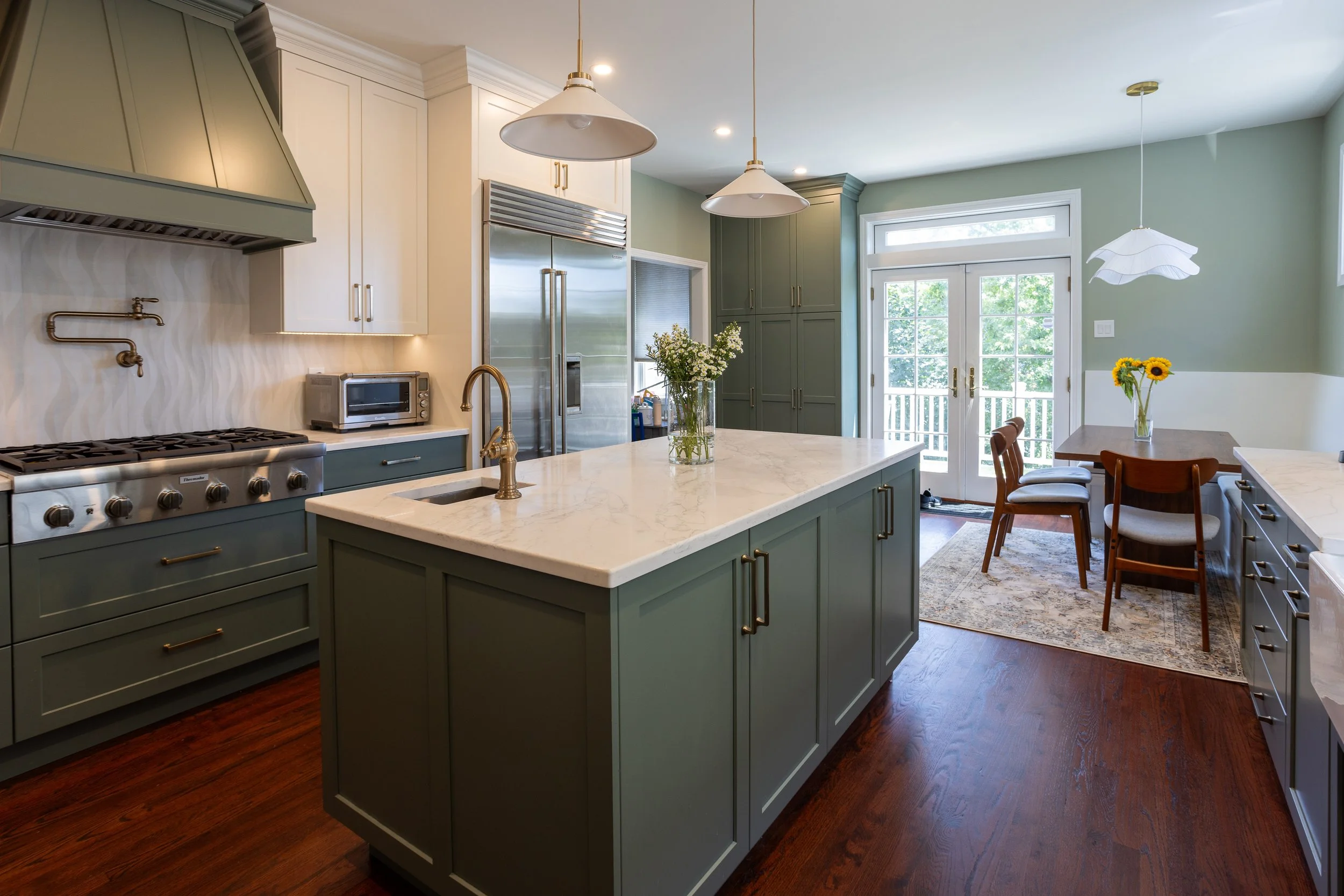 A kitchen with green bases and white upper cabinets and a center island