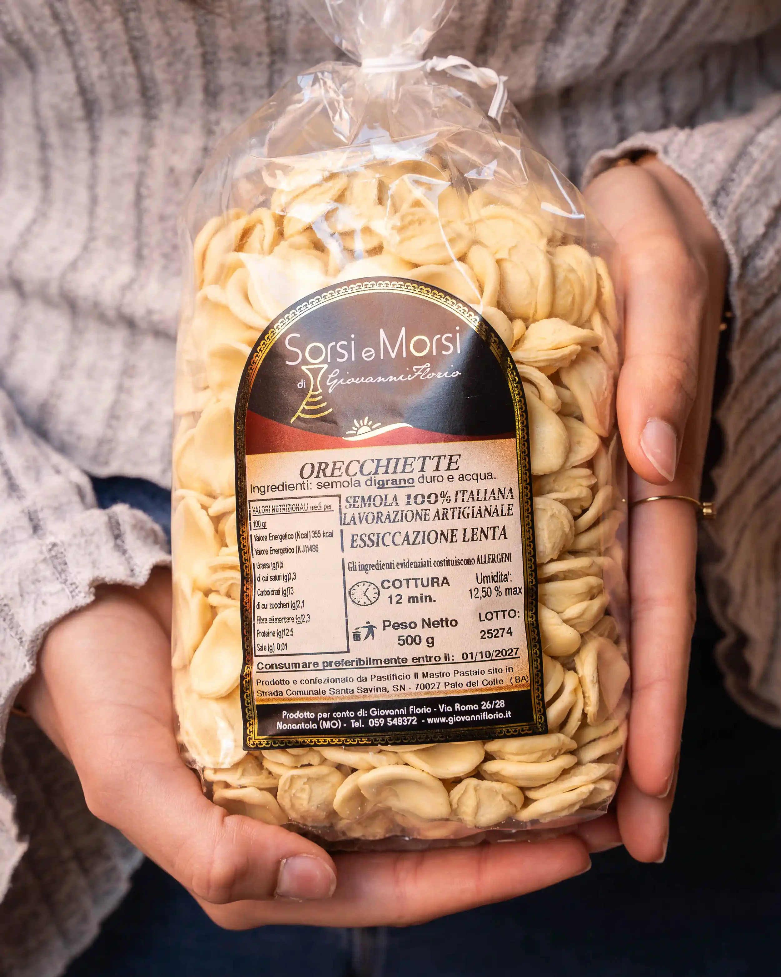 Confezione di orecchiette di semola di grano duro italiano, confezionata da Giovanni Florio, tenuta da una mano di persona vestita con maglione a maniche lunghe. Etichetta bianca con dettagli neri e dorati, descrizione in italiano.