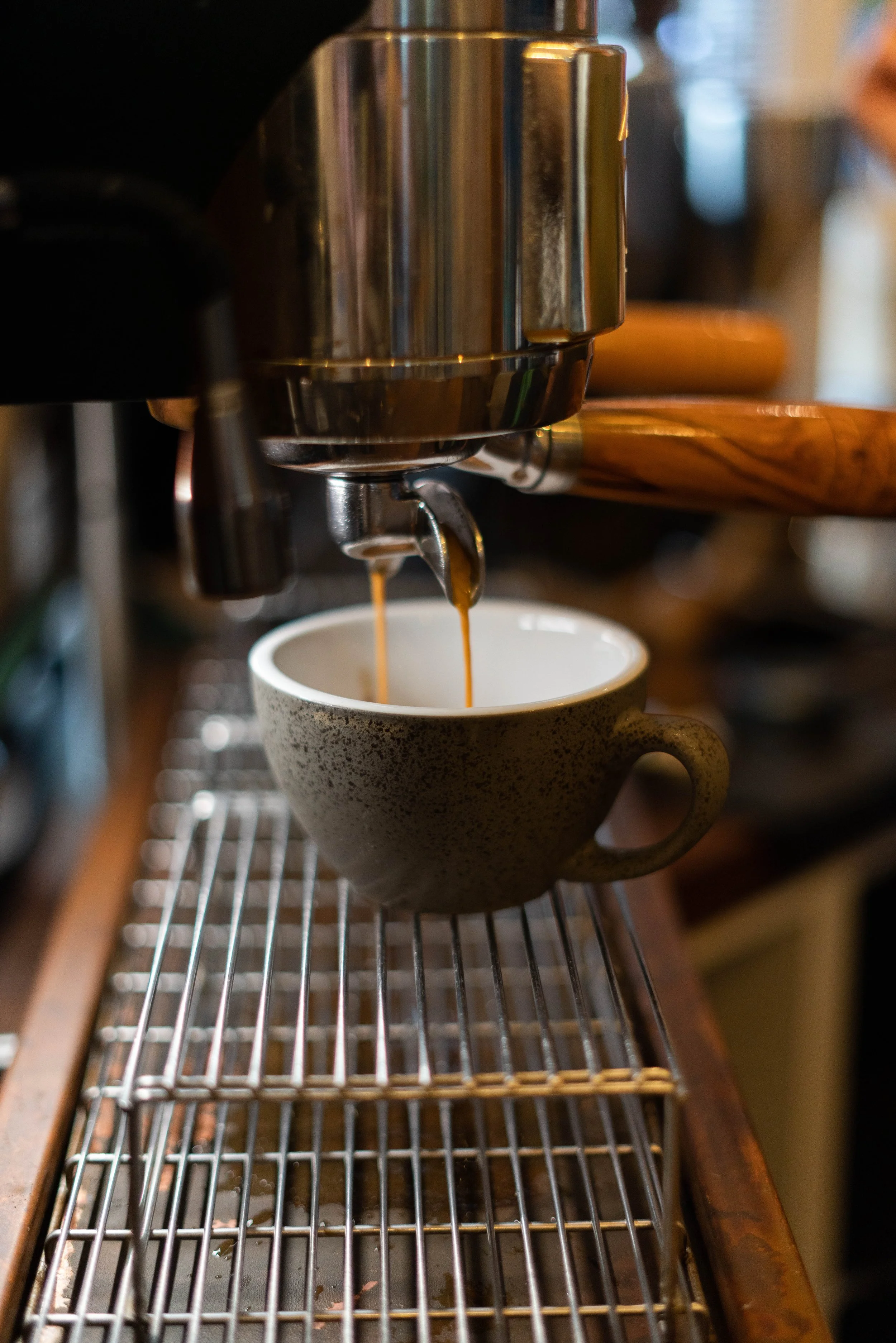 Espresso machine brewing coffee into a ceramic cup.