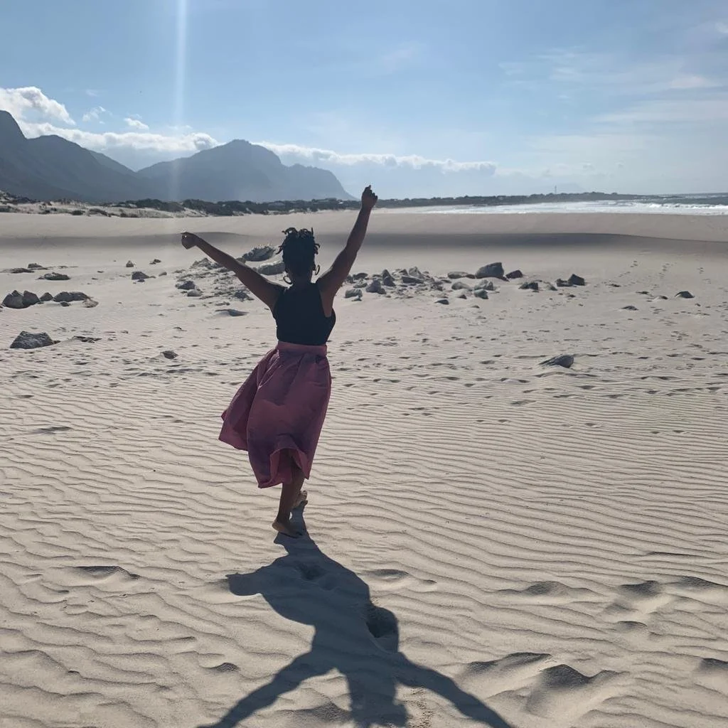 A joyful person with arms raised on the beach in Betty's Bay, South Africa