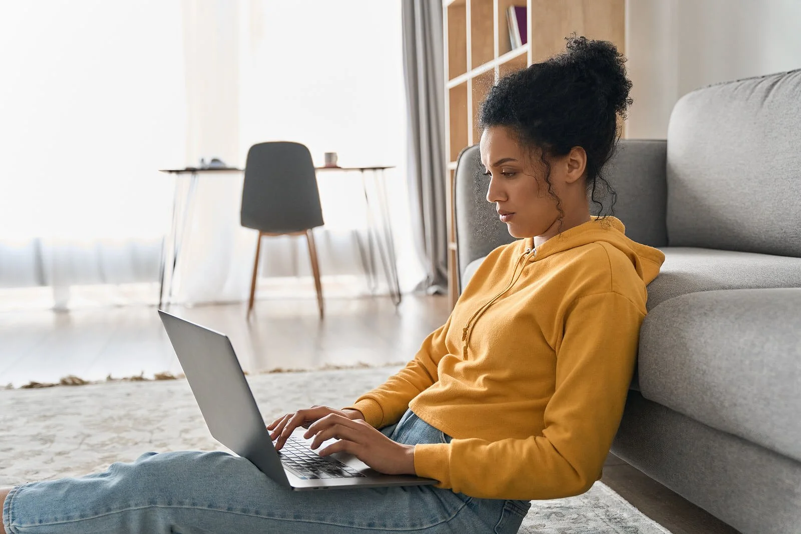 Image of a person sitting on the floor typing on her laptop