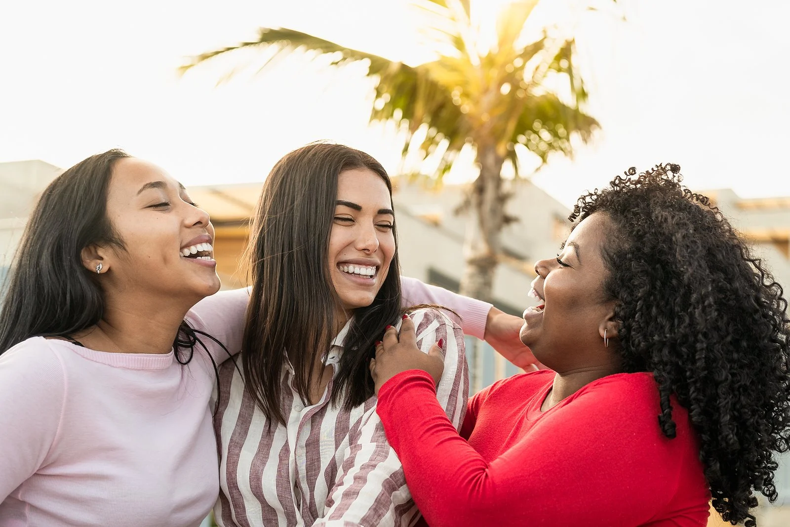 Image of three friends hugging and laughing