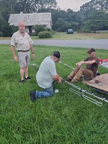 Three men assembling antennas to go on the water tower.