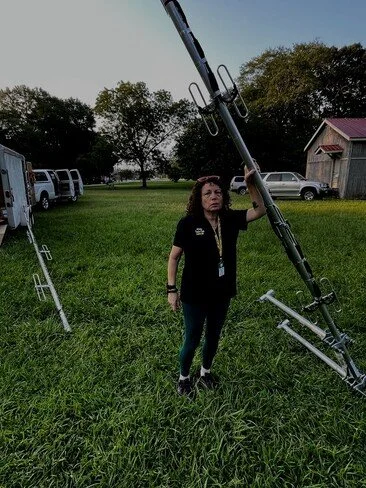 Kathleen, KN4iJM, holding up one of the antennas, which is three times taller than she is.