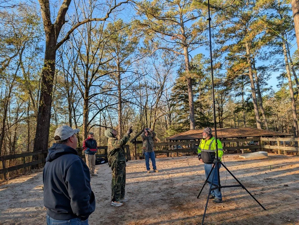 Five ham radio geeks stand in awe pointing at the hex beam antenna.