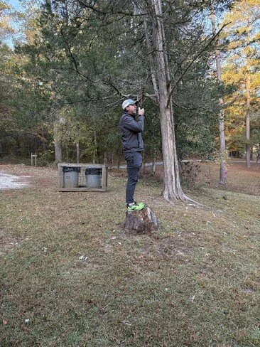 Jesse N4JAH standing on a tree stump talking on his HT.