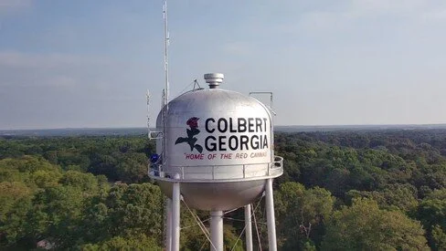 Arial view of the Colbert water tower with the words Colbert Georgia Home of the Red Cannas painted on the tank and showing the clubs two repeater antennas.