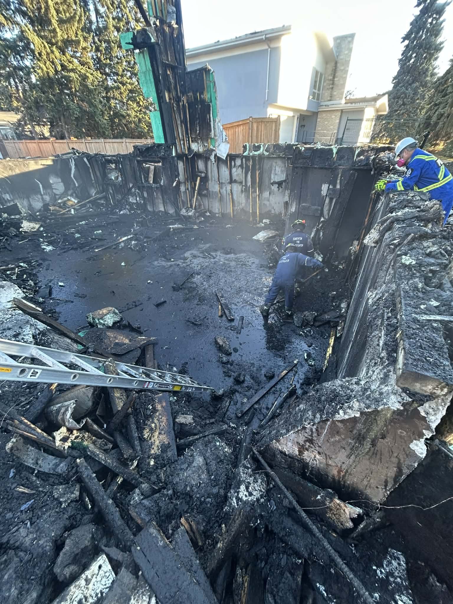 Firefighters investigating the aftermath of a burned residential swimming pool that was destroyed by fire.
